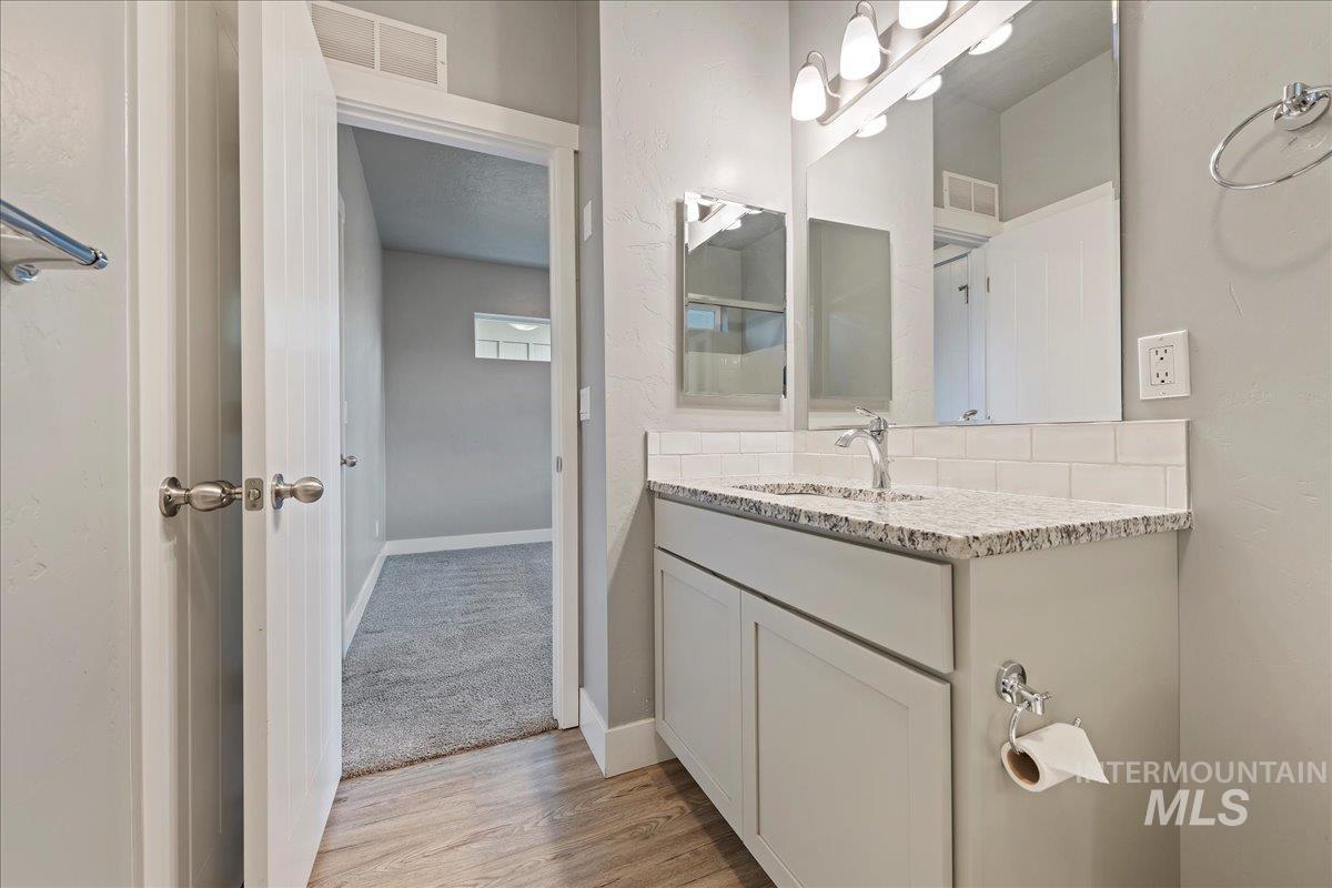 Bathroom with vanity, light wood finished floors, and light colored carpet