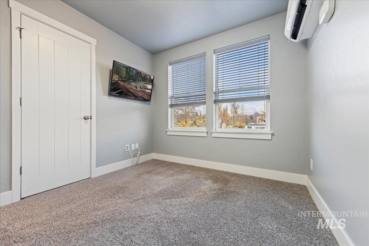 Unfurnished bedroom featuring carpet and a wall unit AC