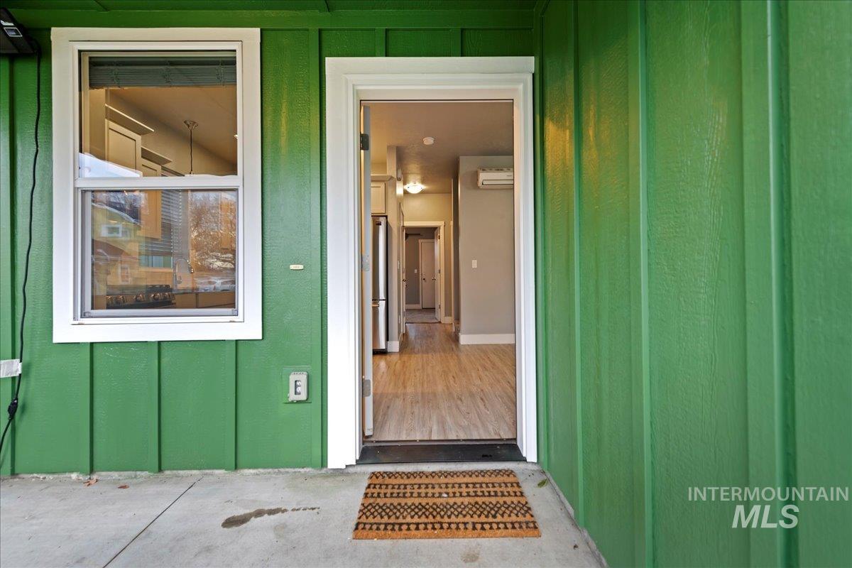 View of exterior entry featuring board and batten siding and an AC wall unit