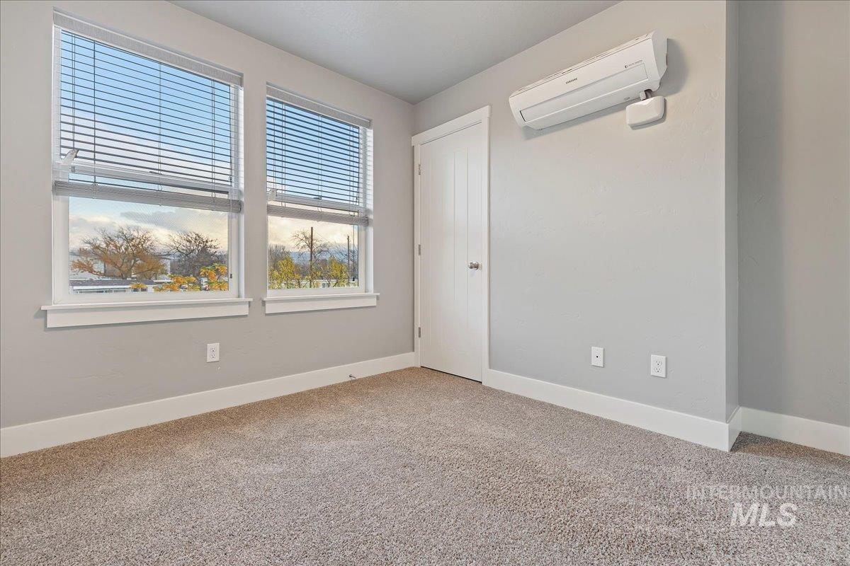 Spare room featuring light carpet and a wall mounted AC