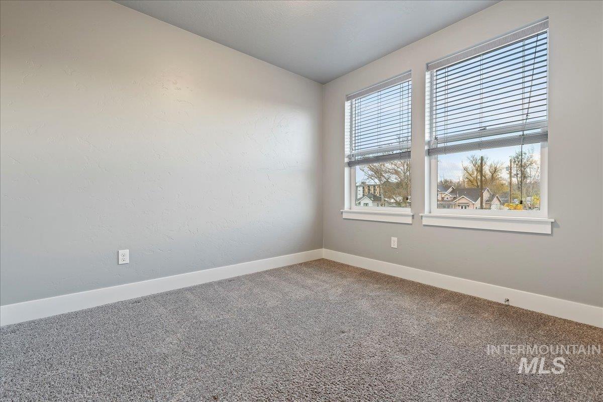 Carpeted spare room featuring baseboards