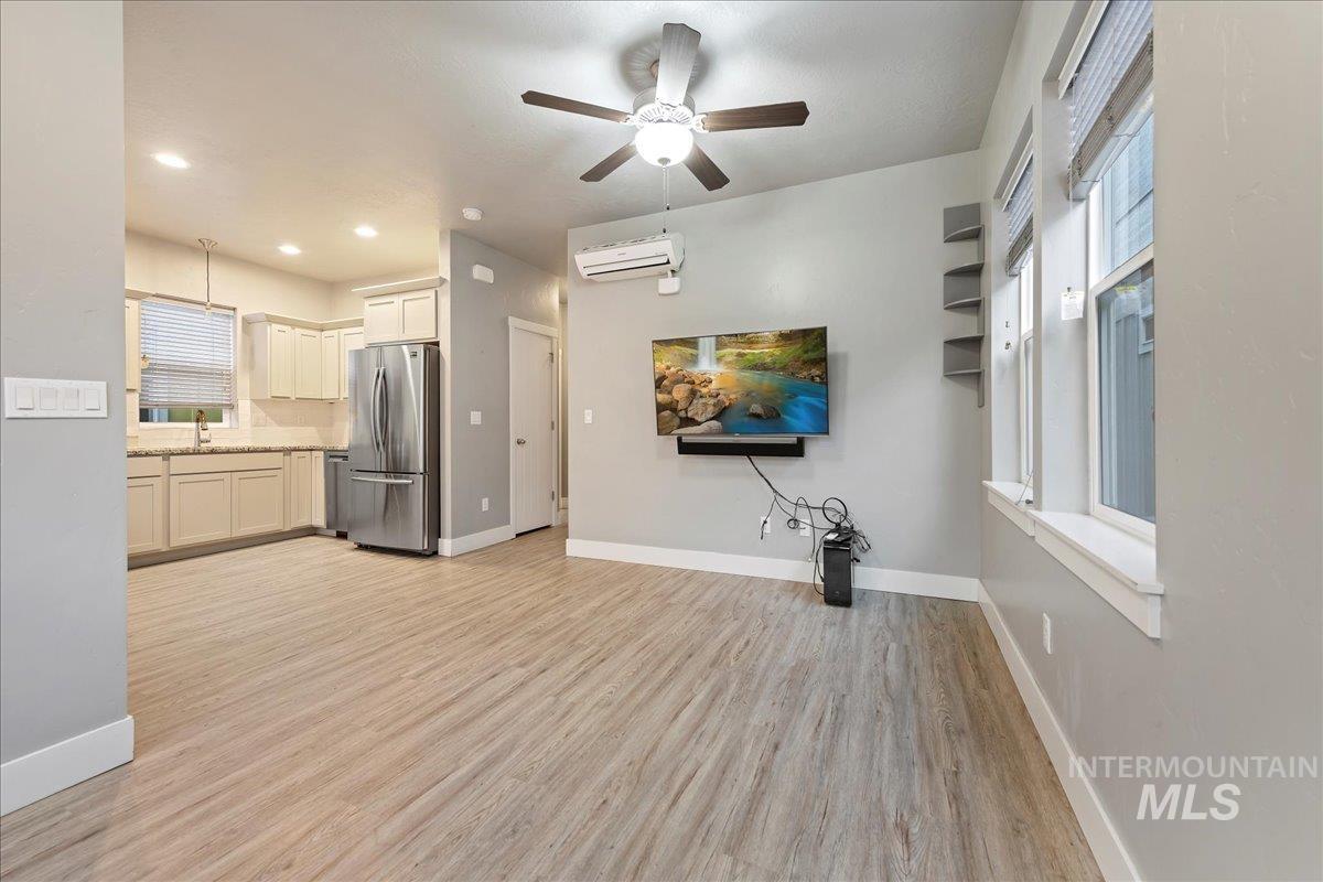 Unfurnished living room featuring ceiling fan, light wood finished floors, a wall mounted air conditioner, and recessed lighting