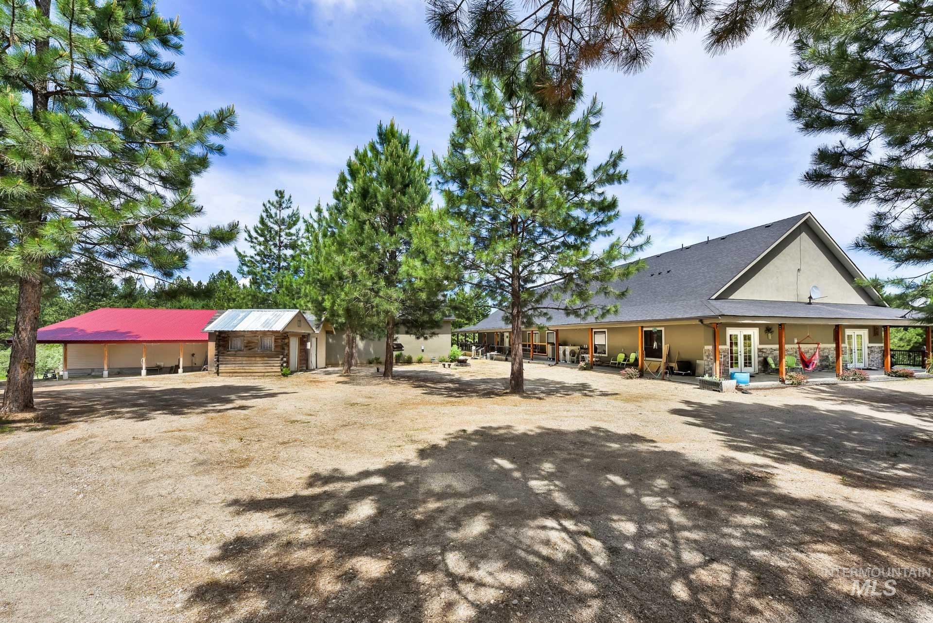 Rear view of house featuring French doors & stucco siding, small outbuildings for storage, and access to detached garage and shop