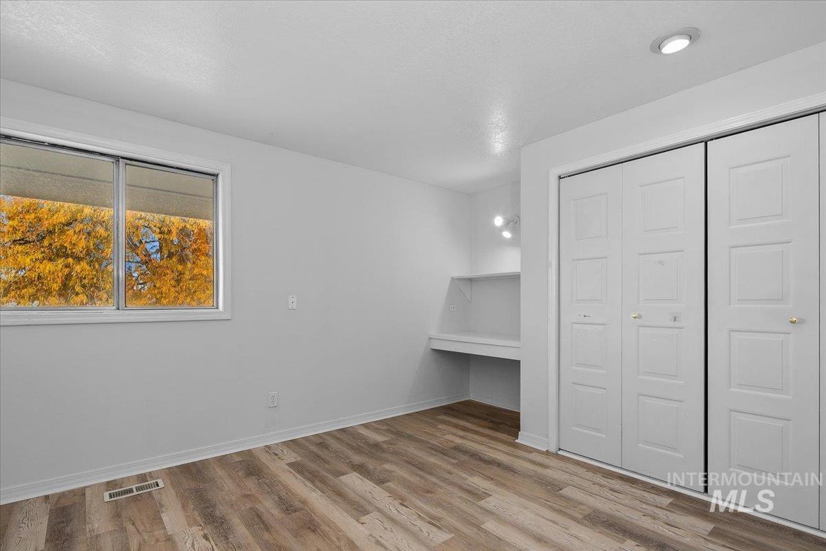 Unfurnished bedroom with light wood-style flooring, a closet, and an office area