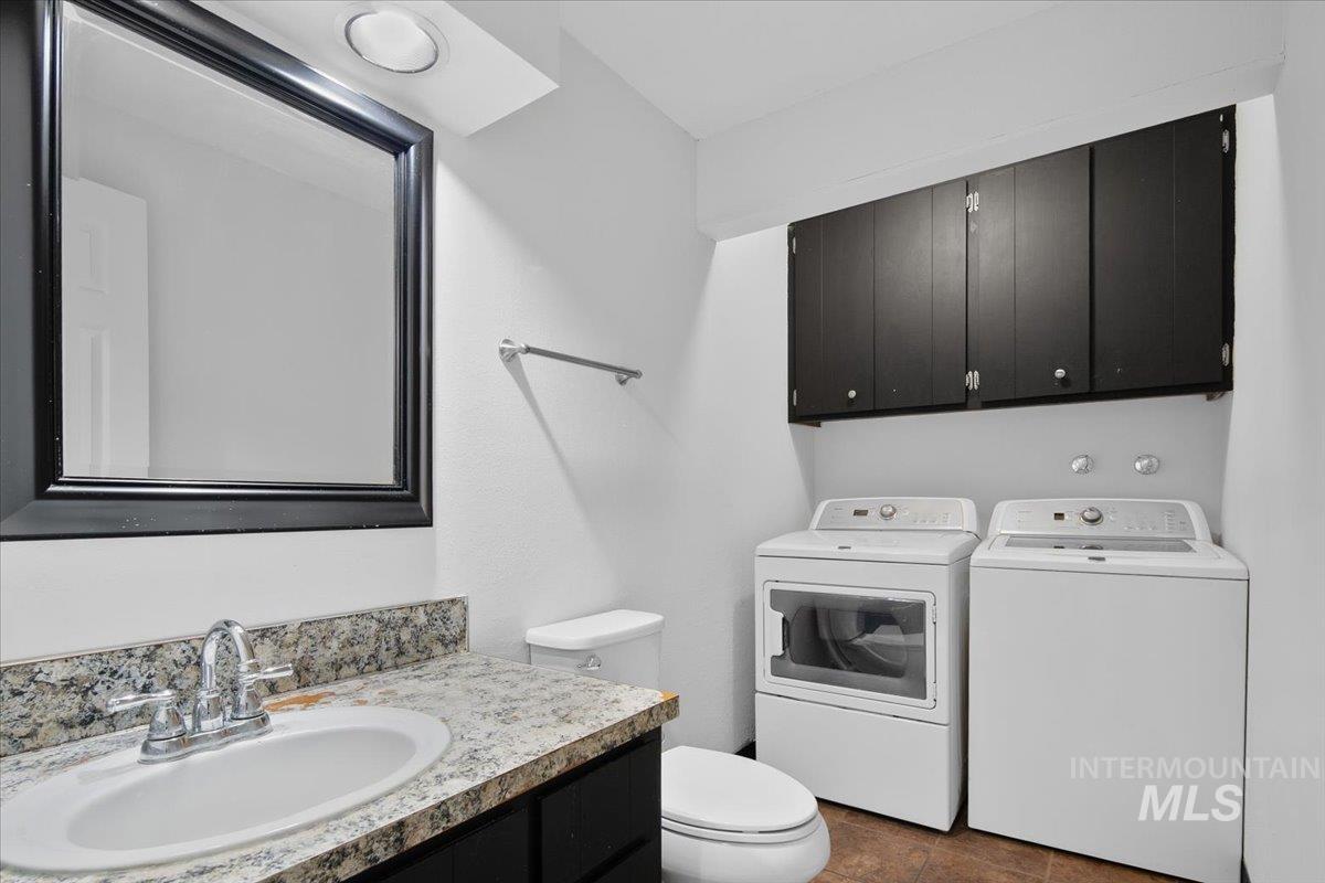 Half bathroom featuring independent washer and dryer, vanity, and dark tile patterned floors