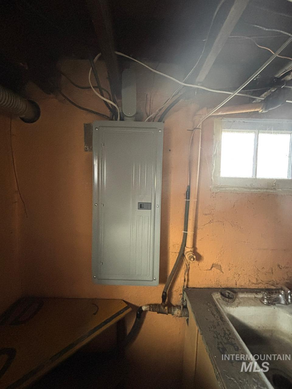 Utility room with electric panel and a sink