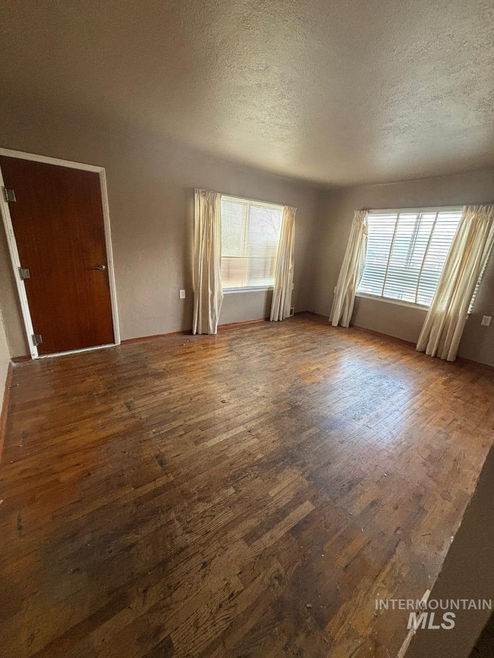 Unfurnished living room with hardwood / wood-style floors and a textured ceiling
