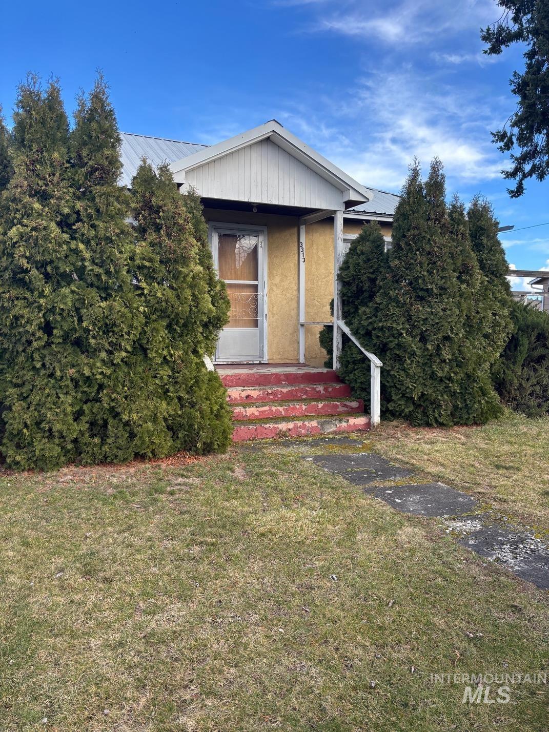 View of front of home with a front lawn, a metal roof, a porch, and stucco siding