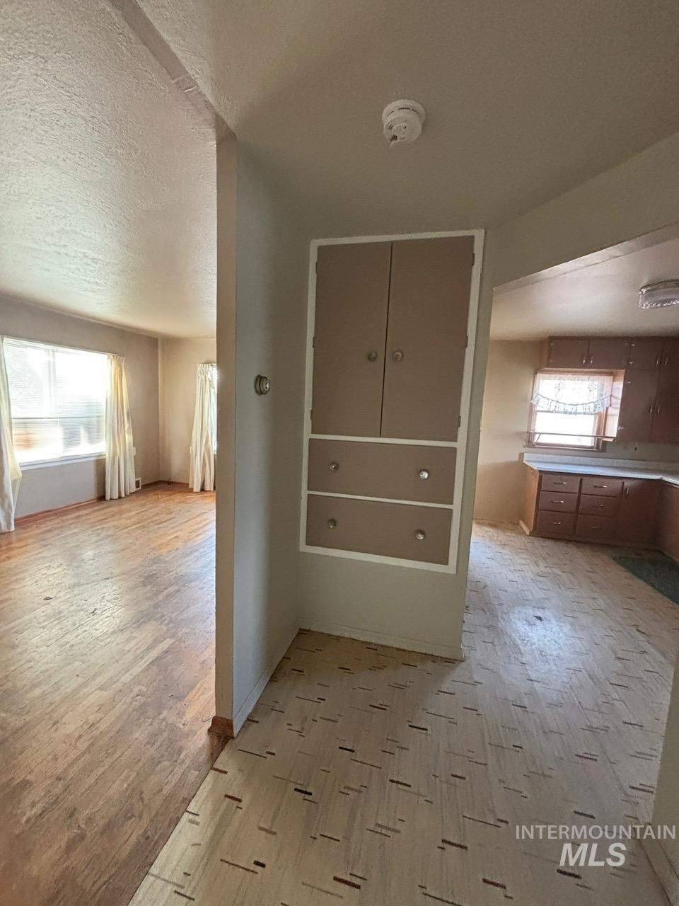 Hallway featuring plenty of natural light, light wood-type flooring, and a textured ceiling