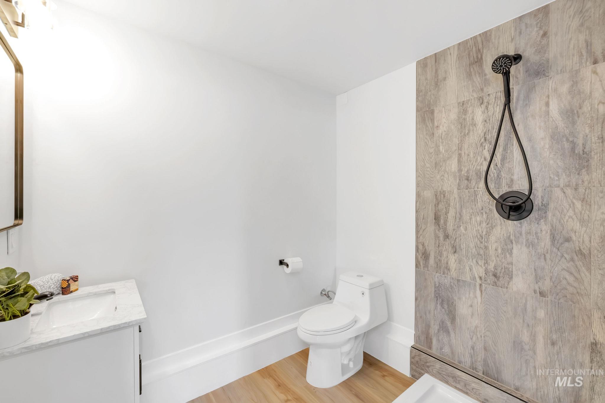 Full bathroom with tiled shower, vanity, and wood finished floors