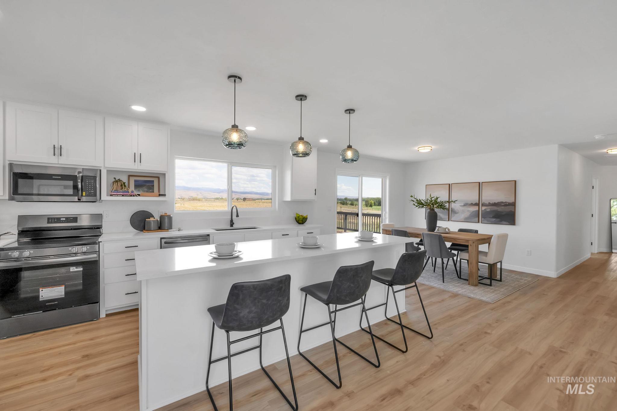 Kitchen featuring appliances with stainless steel finishes, a breakfast bar, light countertops, white cabinetry, and recessed lighting