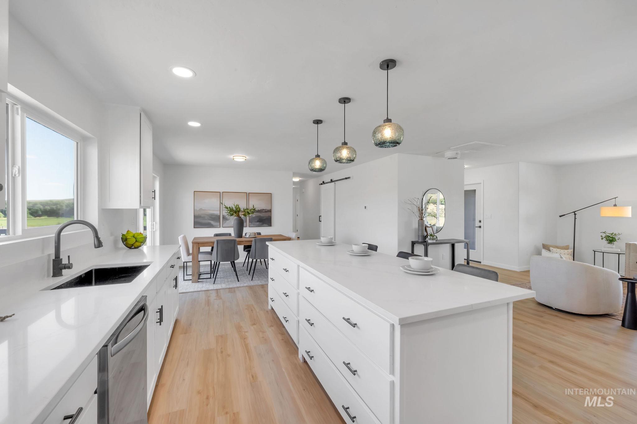 Kitchen featuring light wood-style flooring, dishwasher, white cabinetry, a center island, and decorative light fixtures