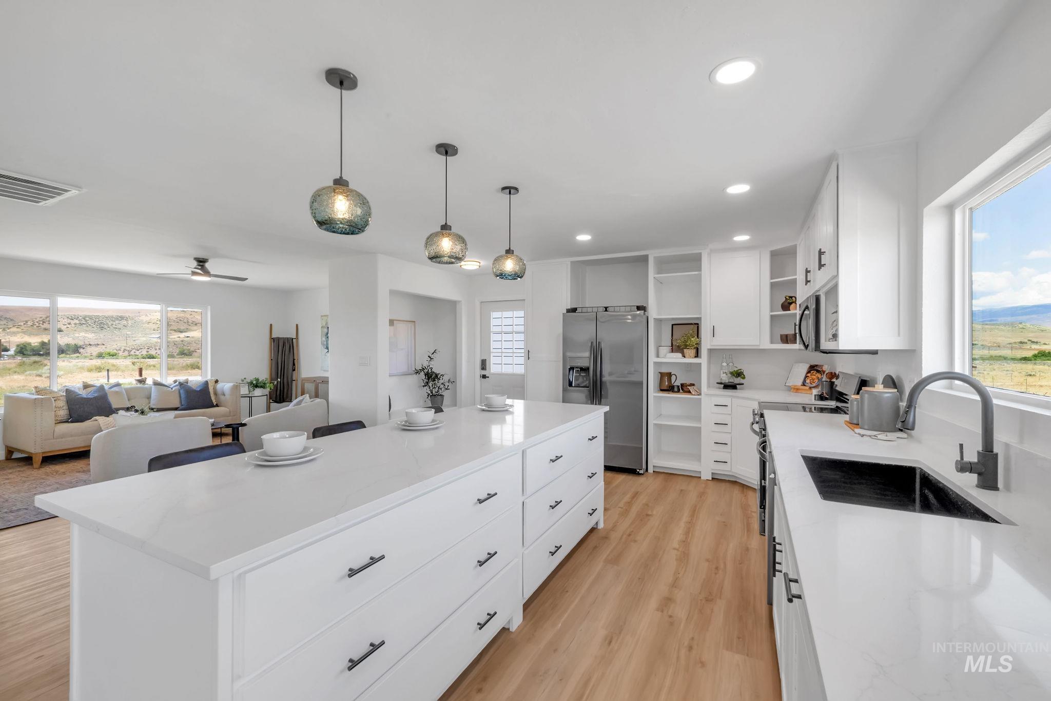 Kitchen with open shelves, stainless steel refrigerator with ice dispenser, light wood-style flooring, recessed lighting, and a center island