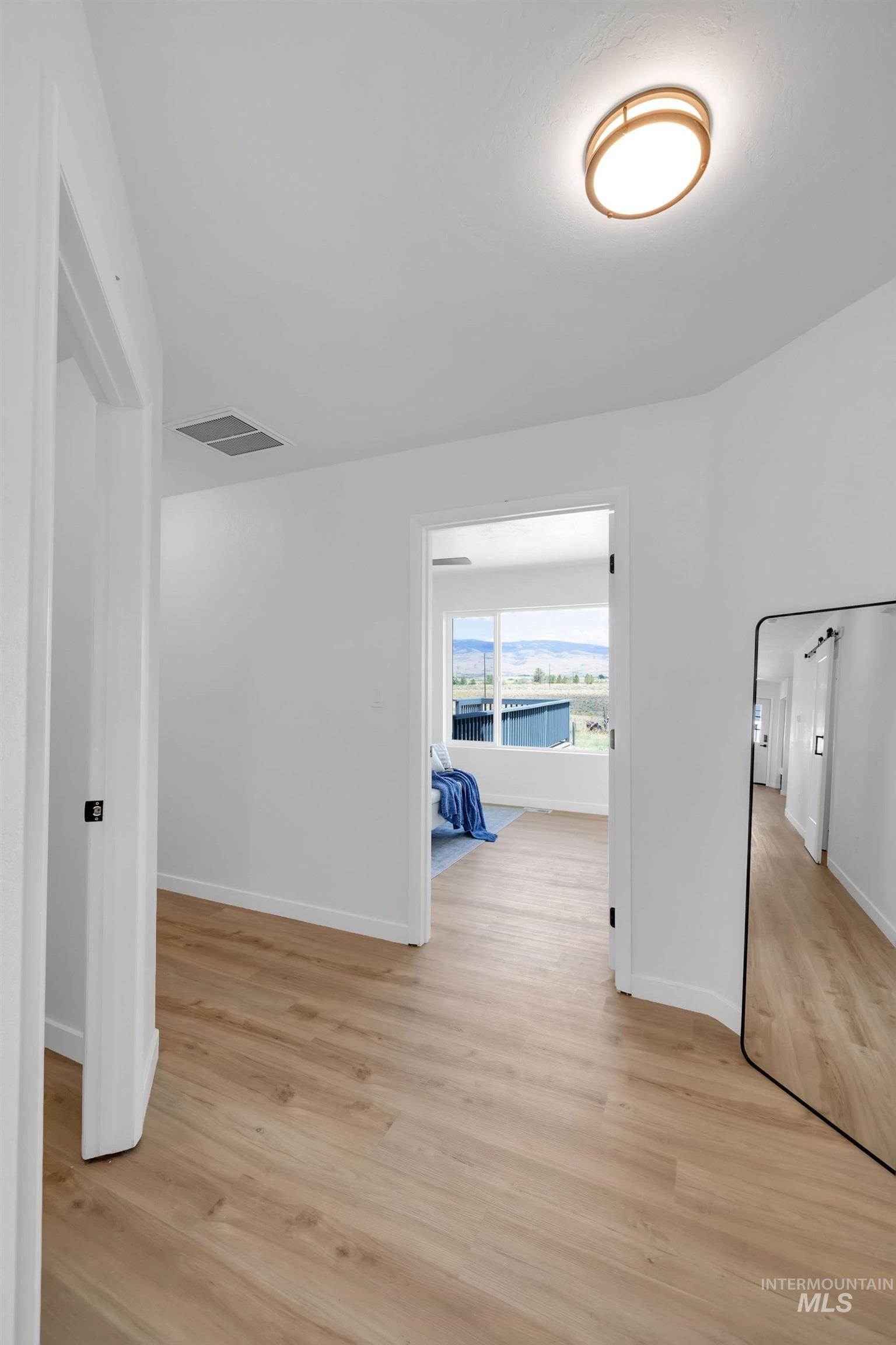 Corridor featuring light wood-style flooring and baseboards