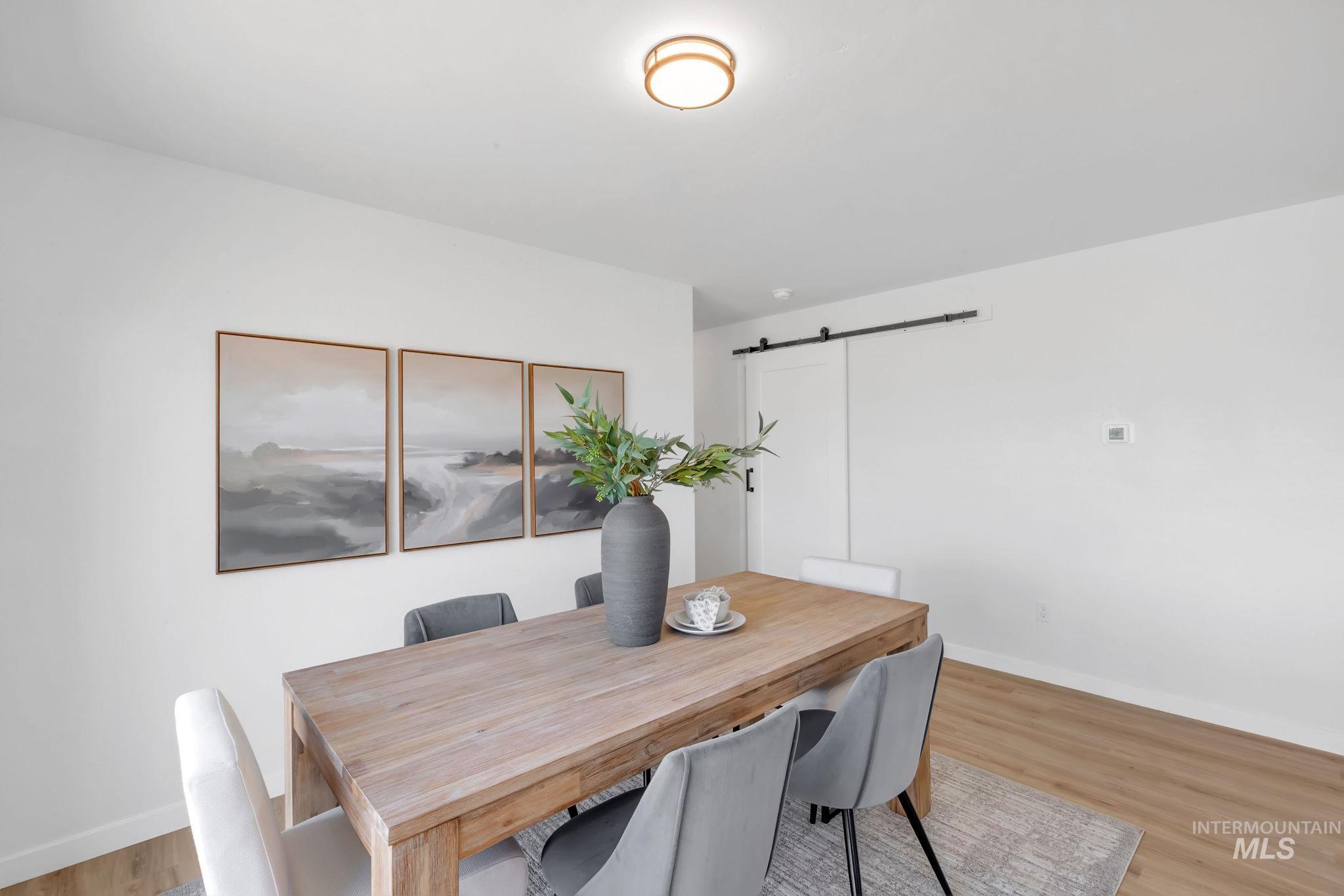 Dining space featuring a barn door and wood finished floors