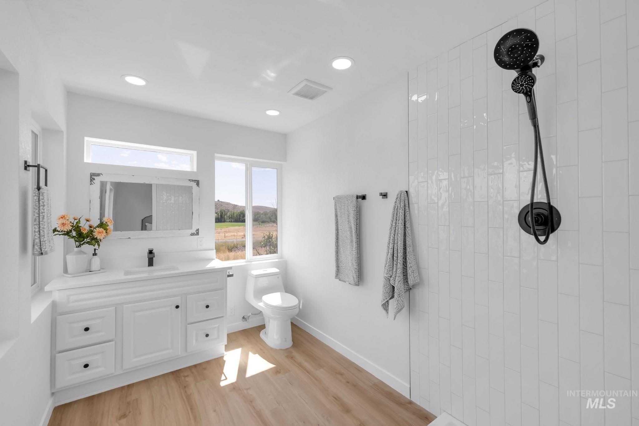 Bathroom featuring a tile shower, vanity, recessed lighting, and wood finished floors