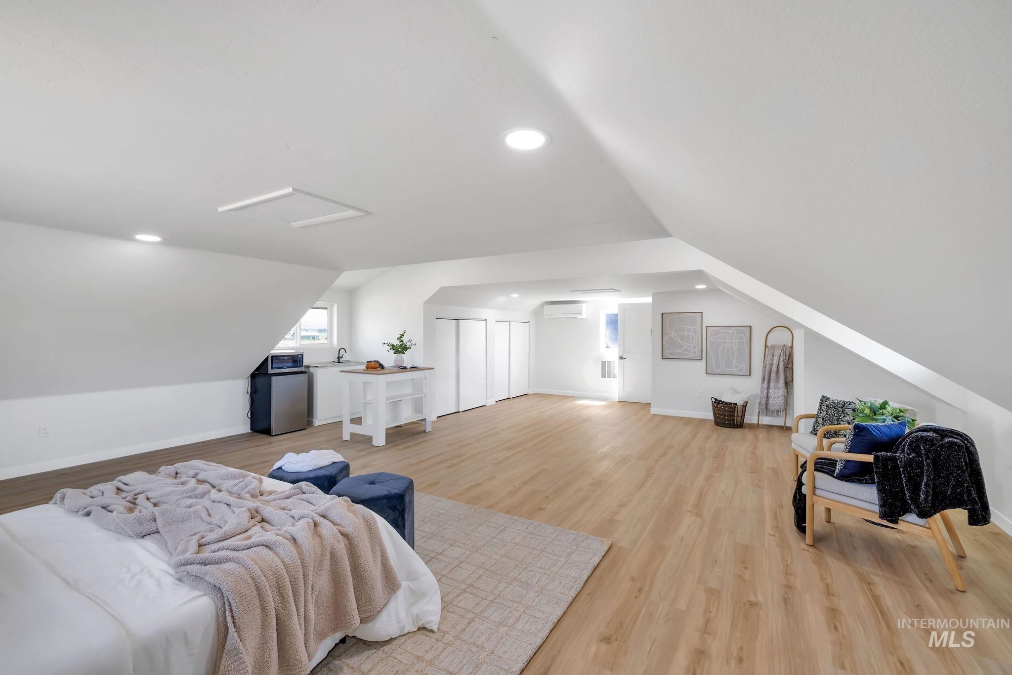 Bedroom featuring recessed lighting, light wood finished floors, vaulted ceiling, and attic access