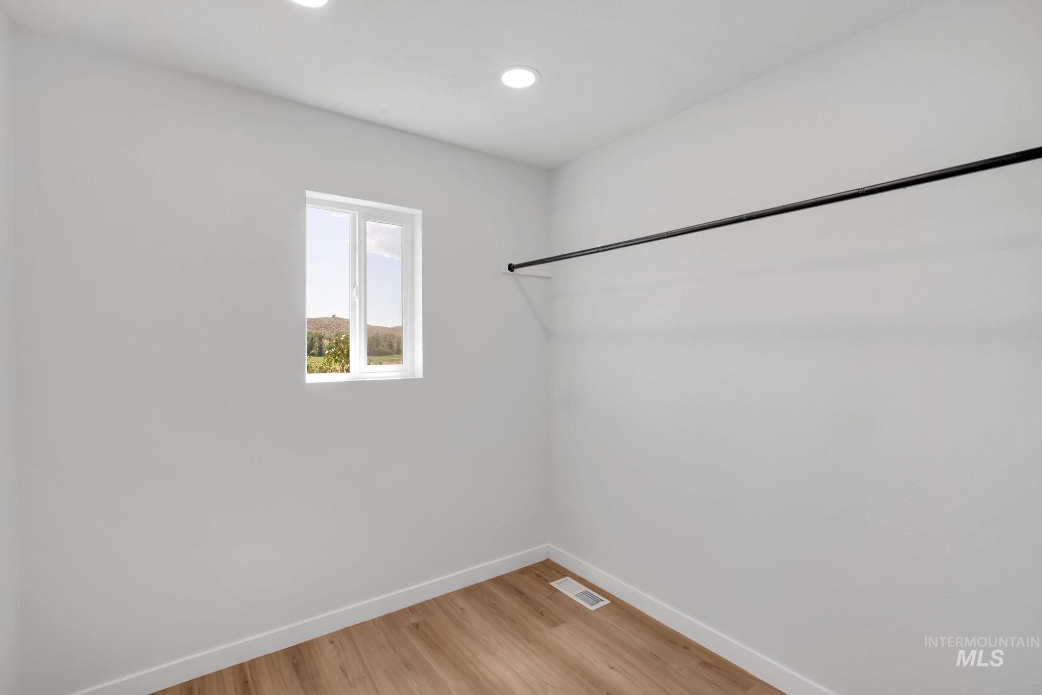 Walk in closet with light wood finished floors