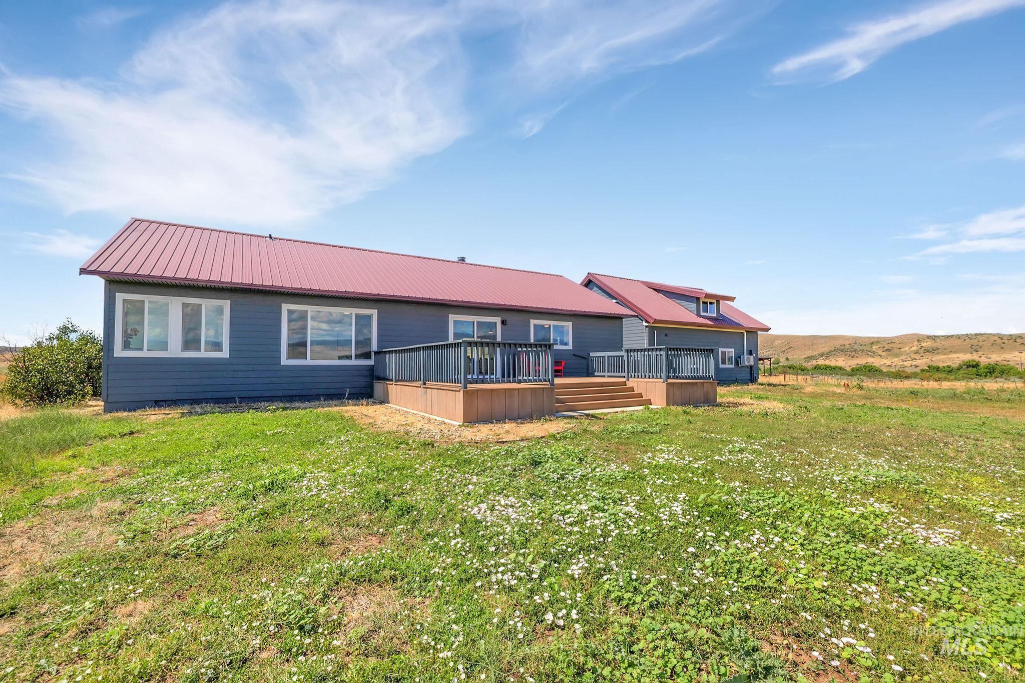 Back of property featuring a wooden deck, a metal roof, and a lawn