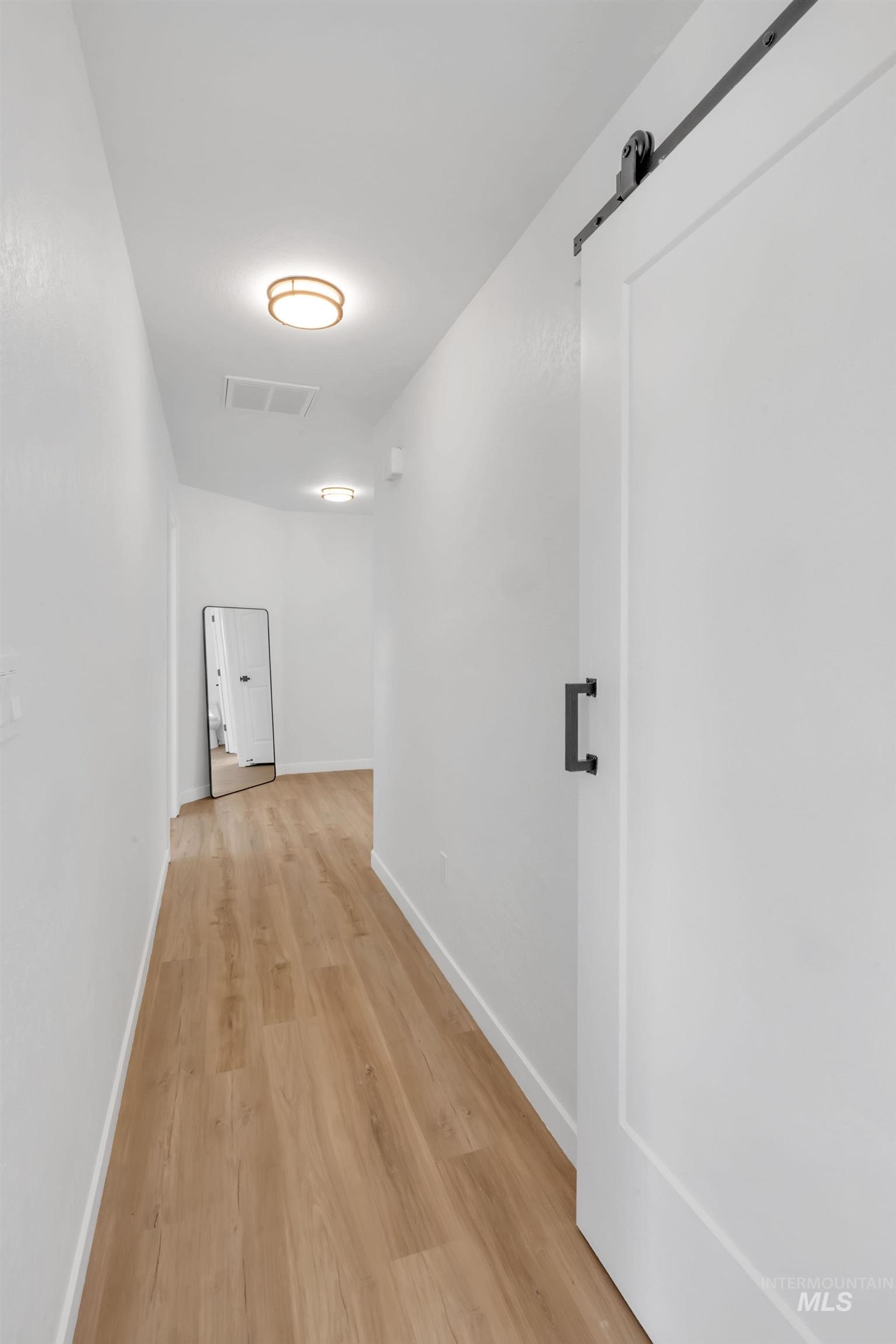 Hallway featuring light wood-style flooring and a barn door