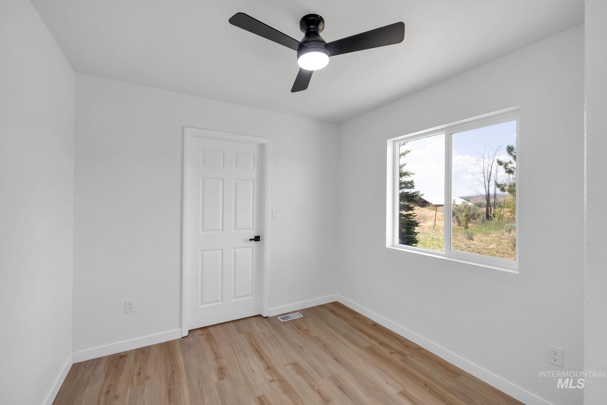 Empty room featuring light wood-style flooring and ceiling fan