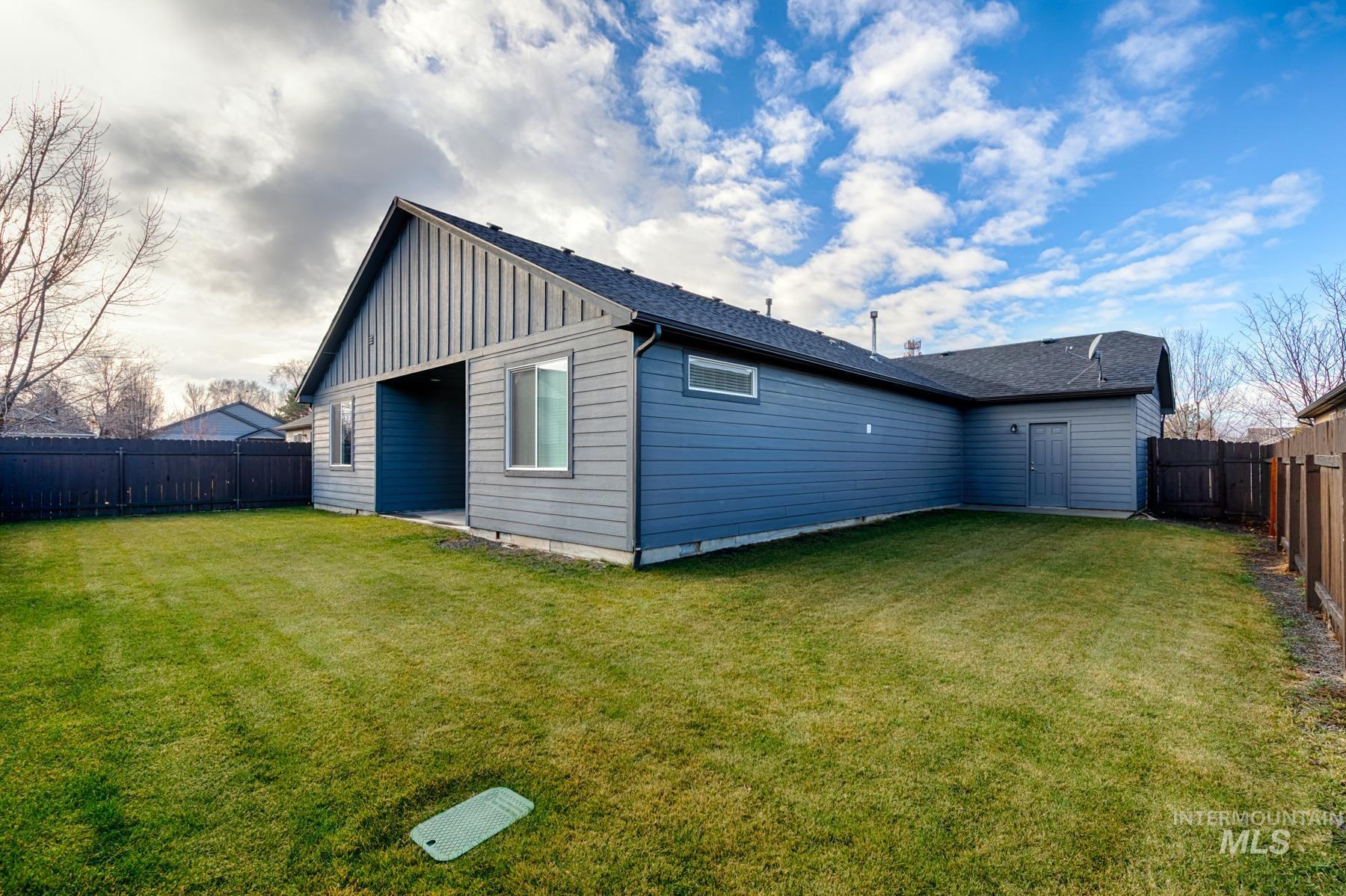 Back of property featuring board and batten siding, a fenced backyard, and roof with shingles