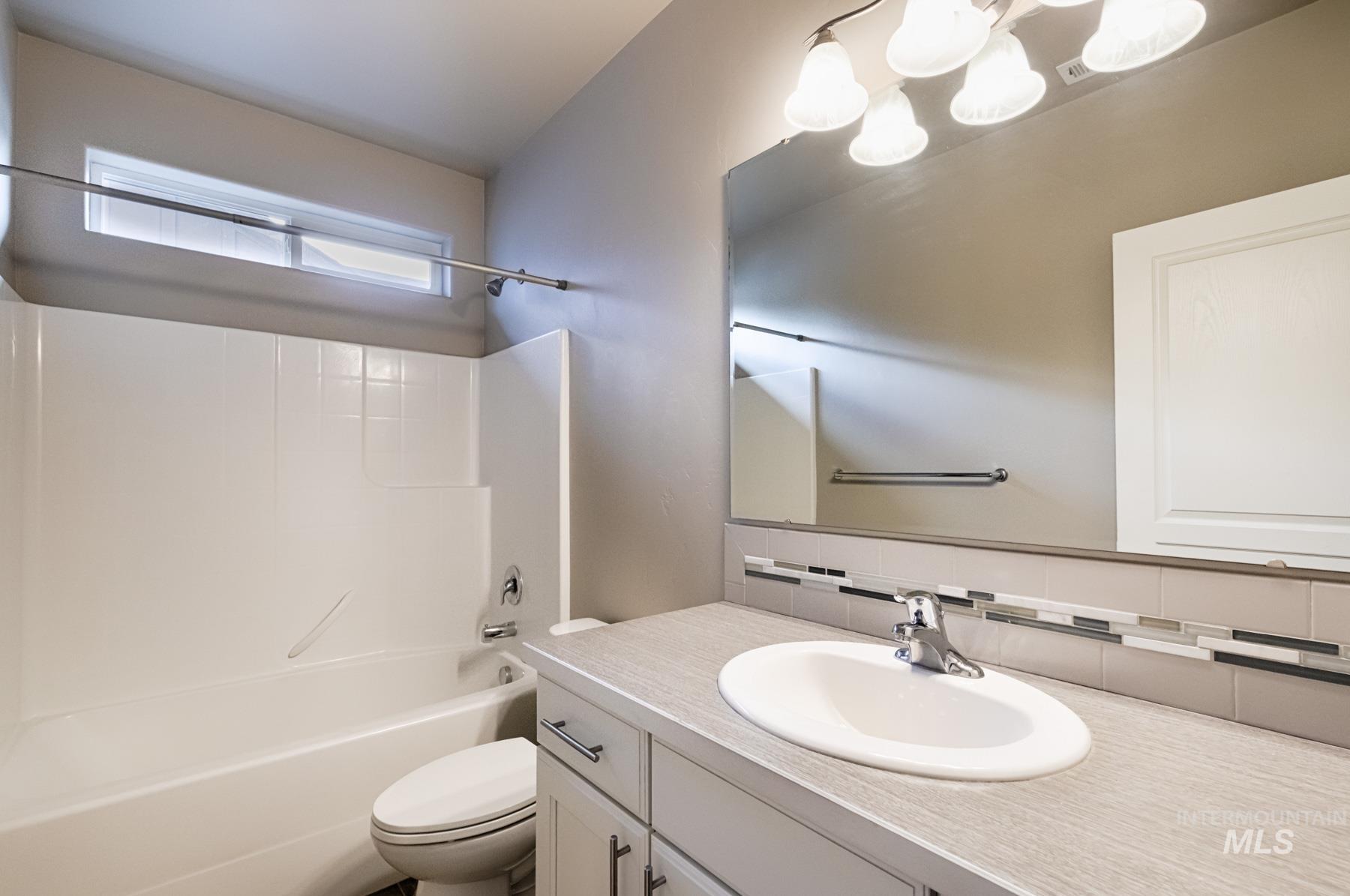 Bathroom with vanity, shower / bath combination, backsplash, and a chandelier