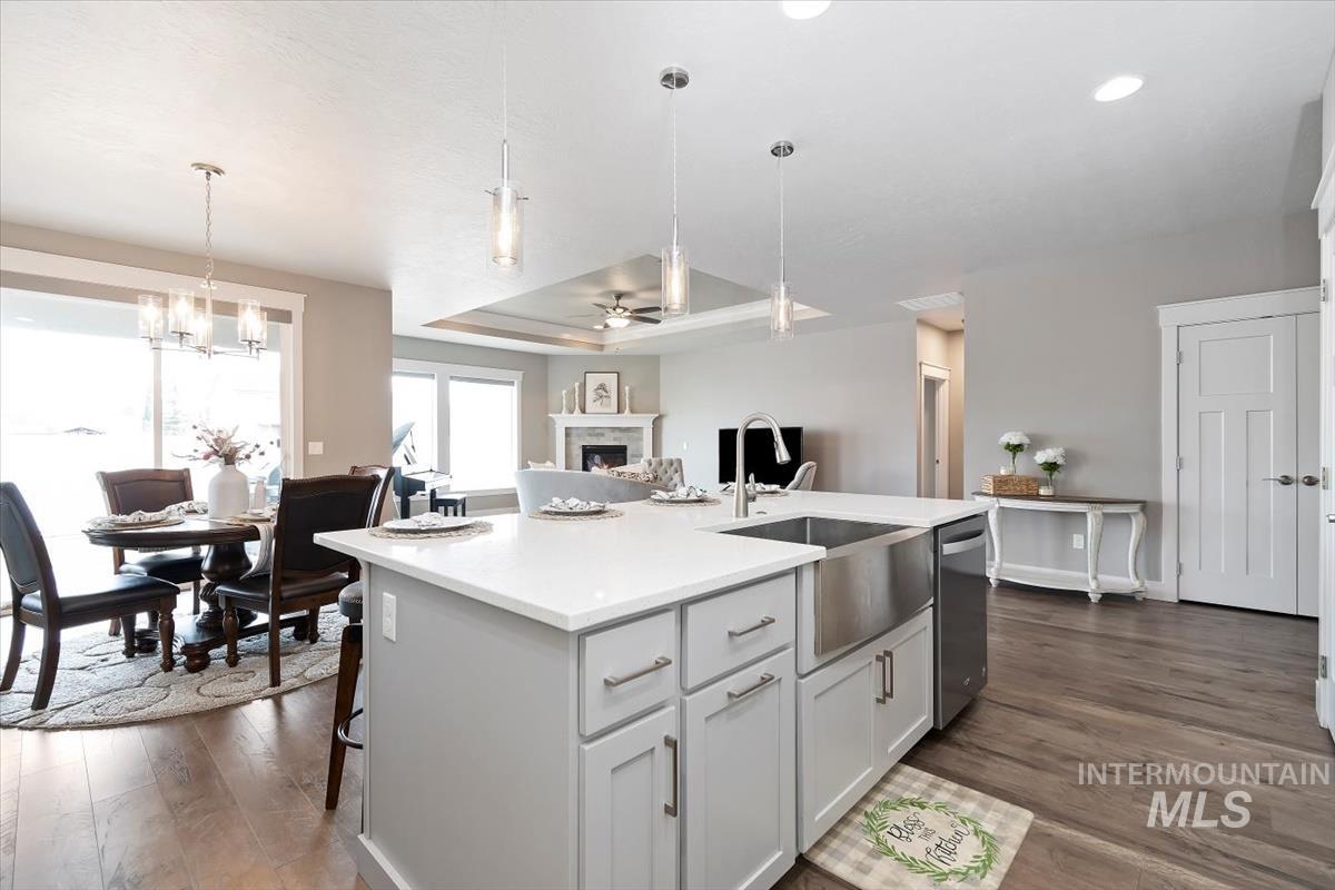 Kitchen featuring ceiling fan, a lit fireplace, a kitchen island with sink, and pendant lighting
