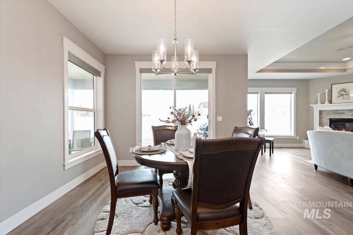 Dining room featuring light wood-type flooring, a chandelier, and a glass covered fireplace