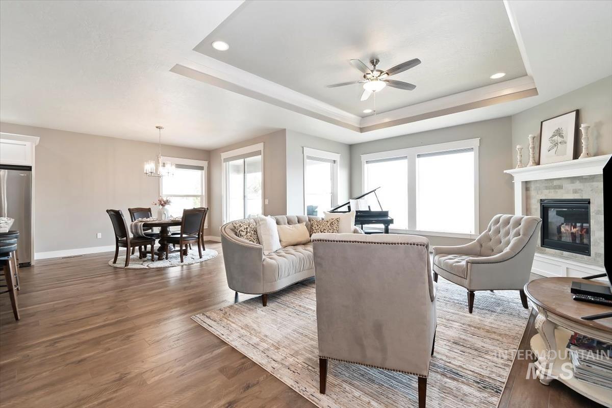Living area featuring a glass covered fireplace, plenty of natural light, a ceiling fan, wood finished floors, and recessed lighting