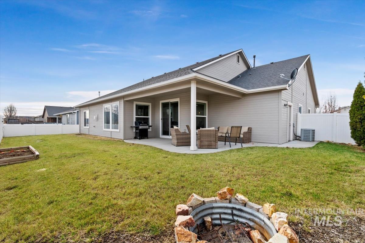 Rear view of house featuring a patio, a fenced backyard, an outdoor living space with a fire pit, and a shingled roof