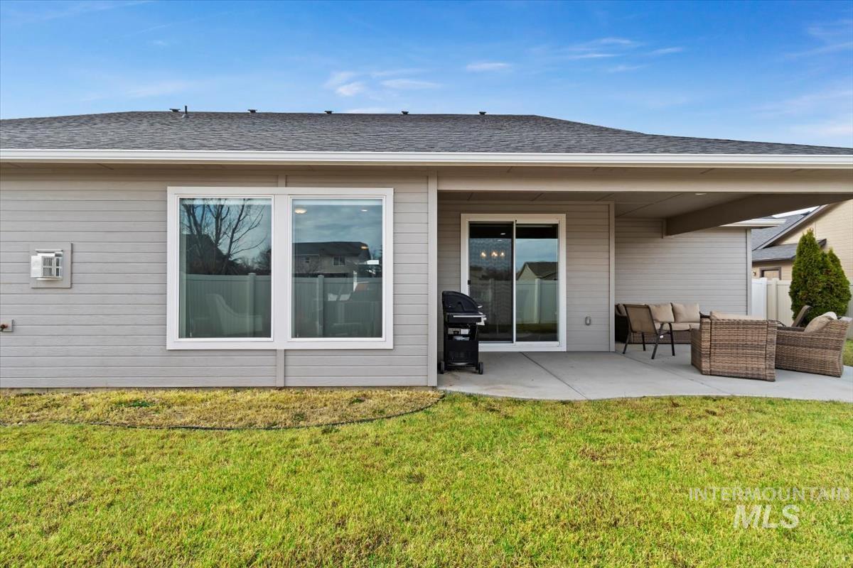 Back of house with an outdoor living space, a patio, a yard, and roof with shingles