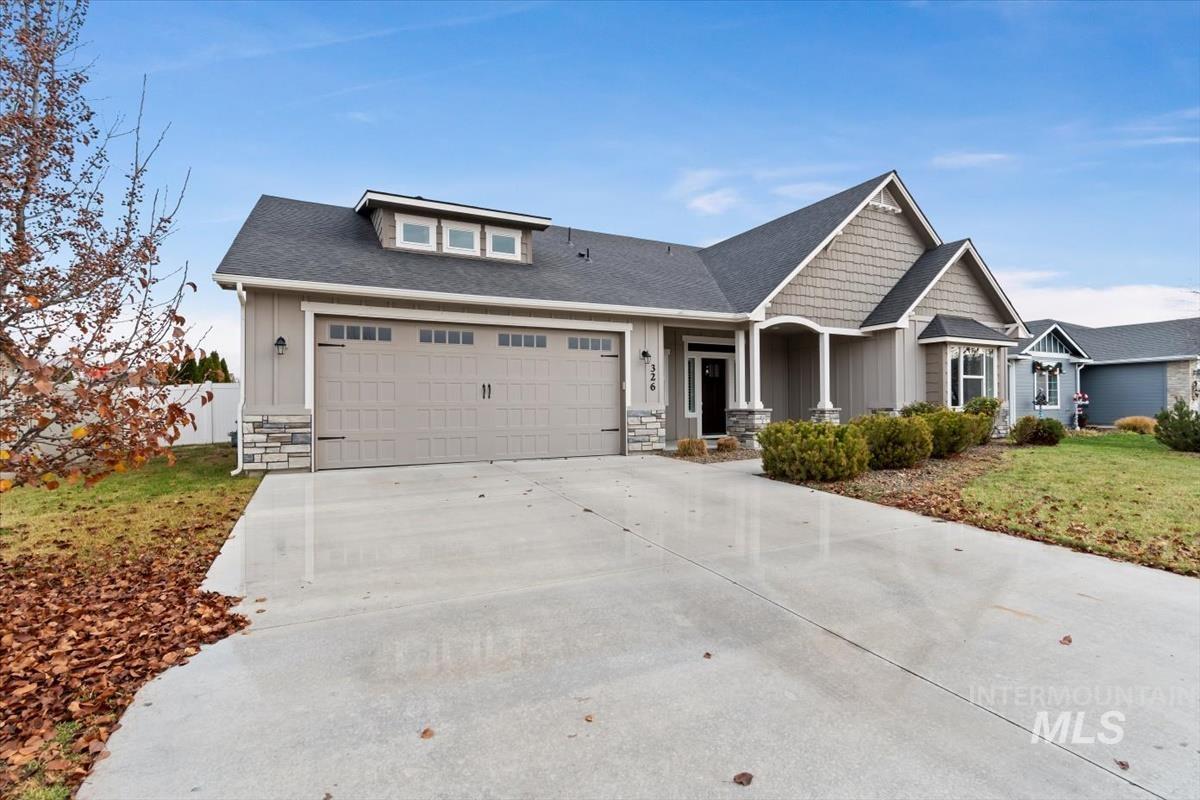 Craftsman-style house featuring stone siding, board and batten siding, driveway, roof with shingles, and a garage