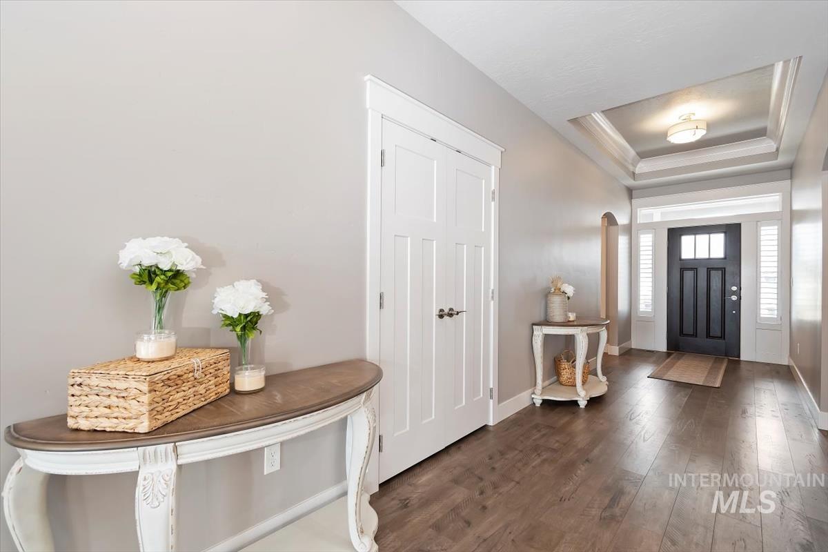 Entrance foyer featuring a tray ceiling and dark wood finished floors