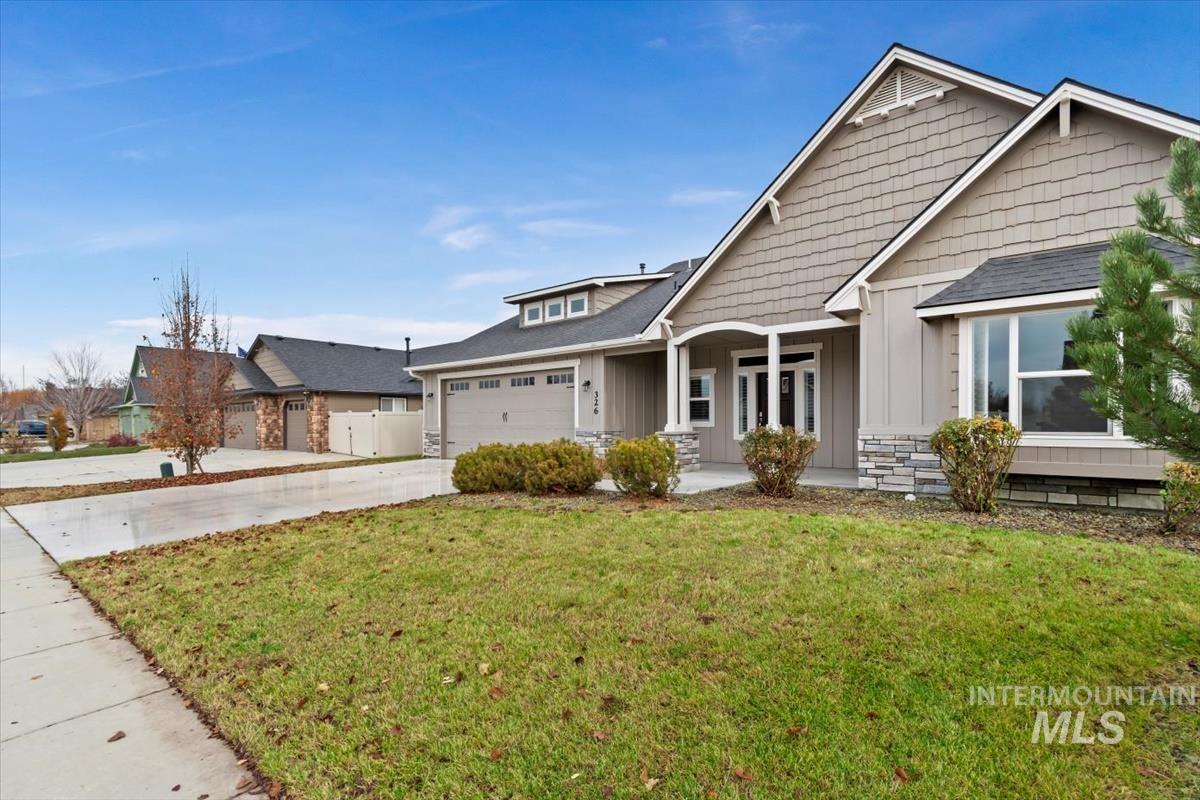 Craftsman inspired home with a front lawn, concrete driveway, board and batten siding, a garage, and covered porch
