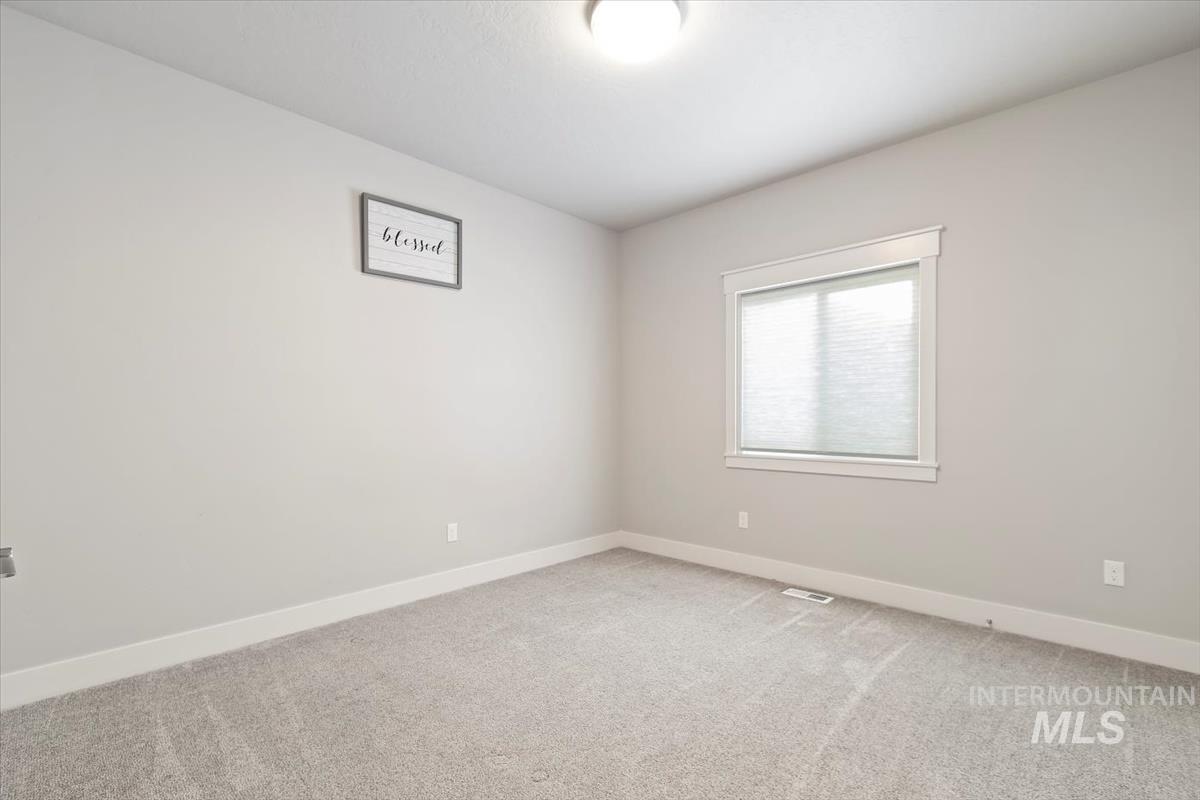 Unfurnished room featuring baseboards and light carpet