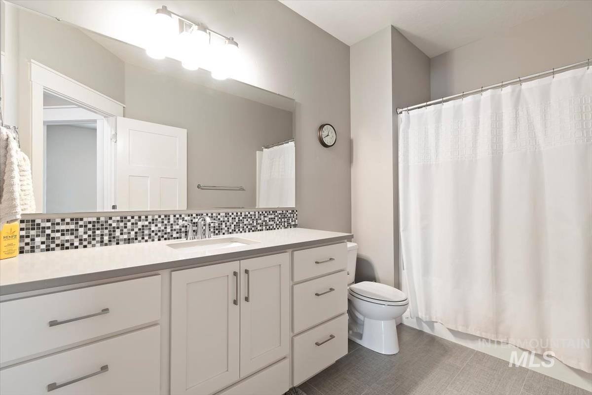 Full bath with vanity and decorative backsplash