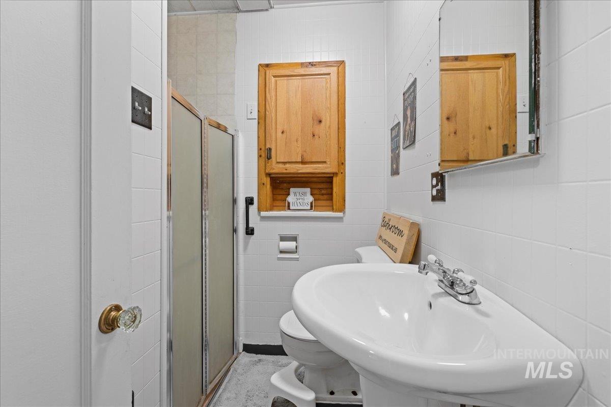 Bathroom featuring a stall shower and tile walls