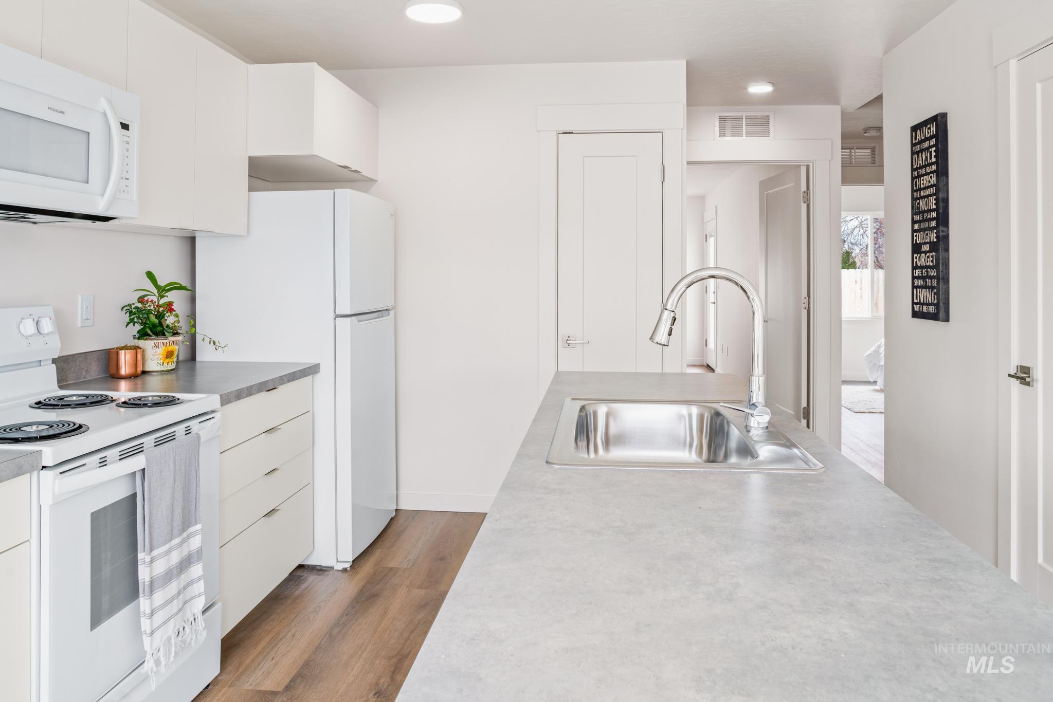 Kitchen featuring white appliances, dark wood finished floors, white cabinets, recessed lighting, and modern cabinets