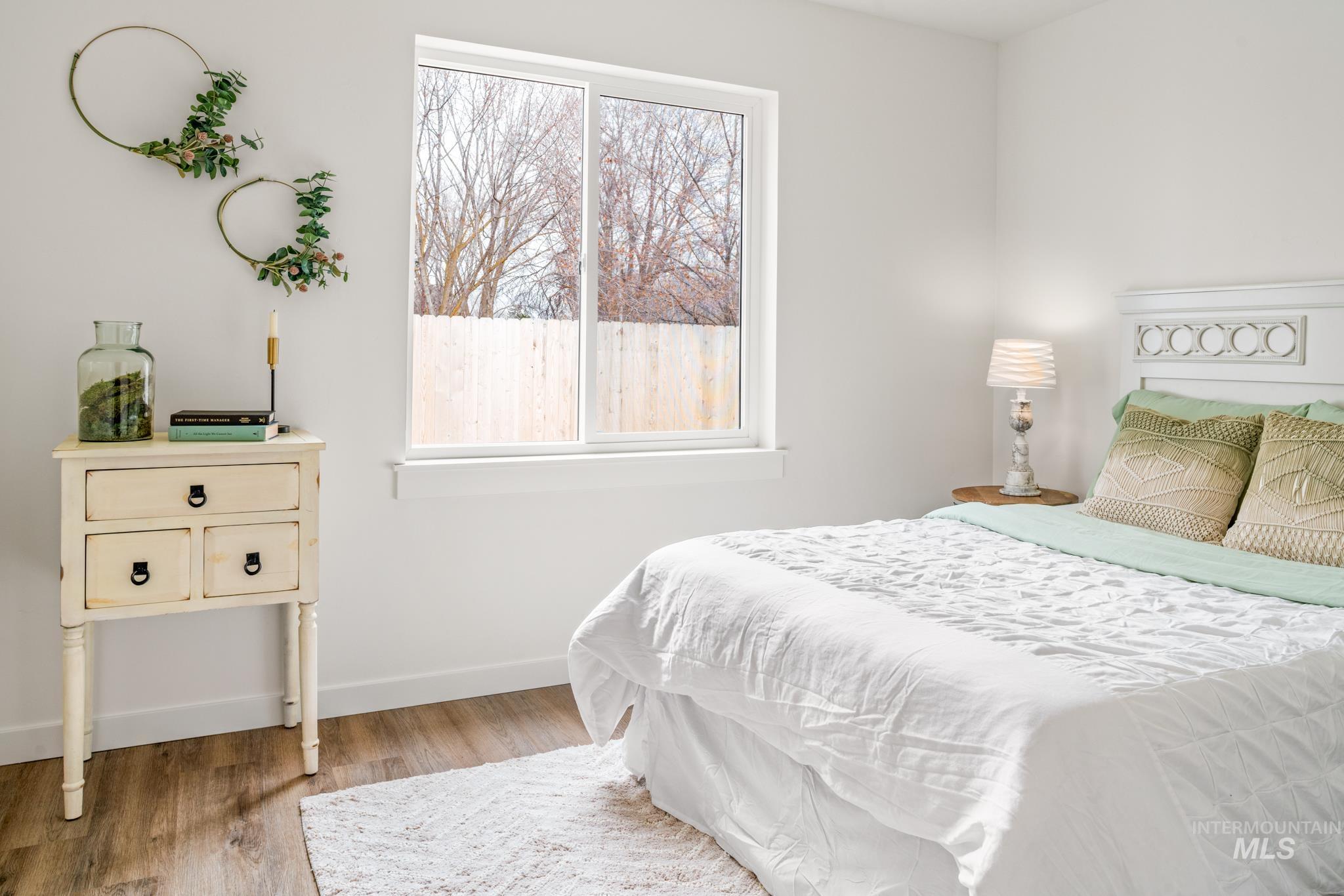 Bedroom with multiple windows and light wood-style floors