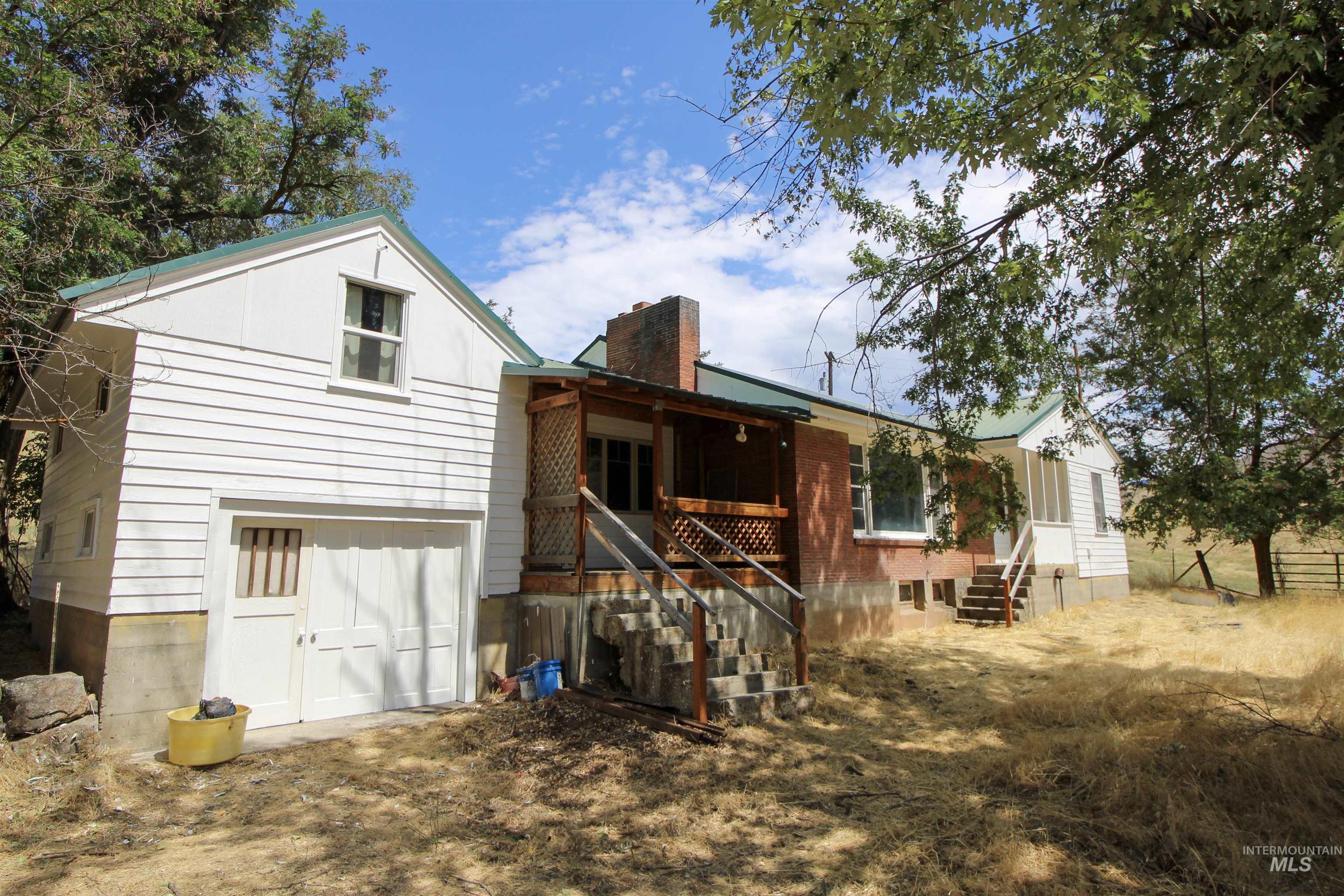 Rear view of property with a chimney, covered porch, and an attached garage