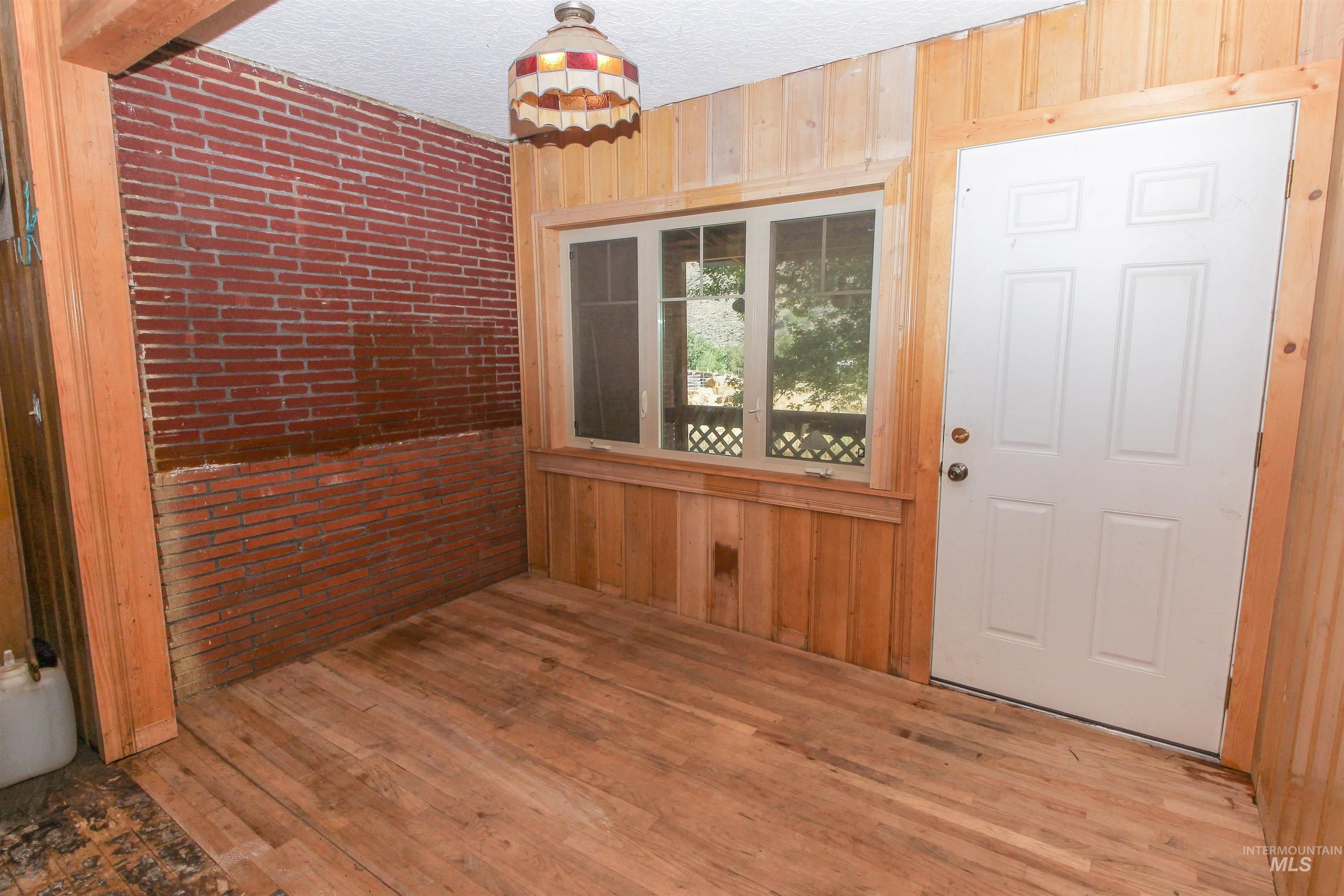 Foyer with wooden walls, wood-type flooring, and a textured ceiling
