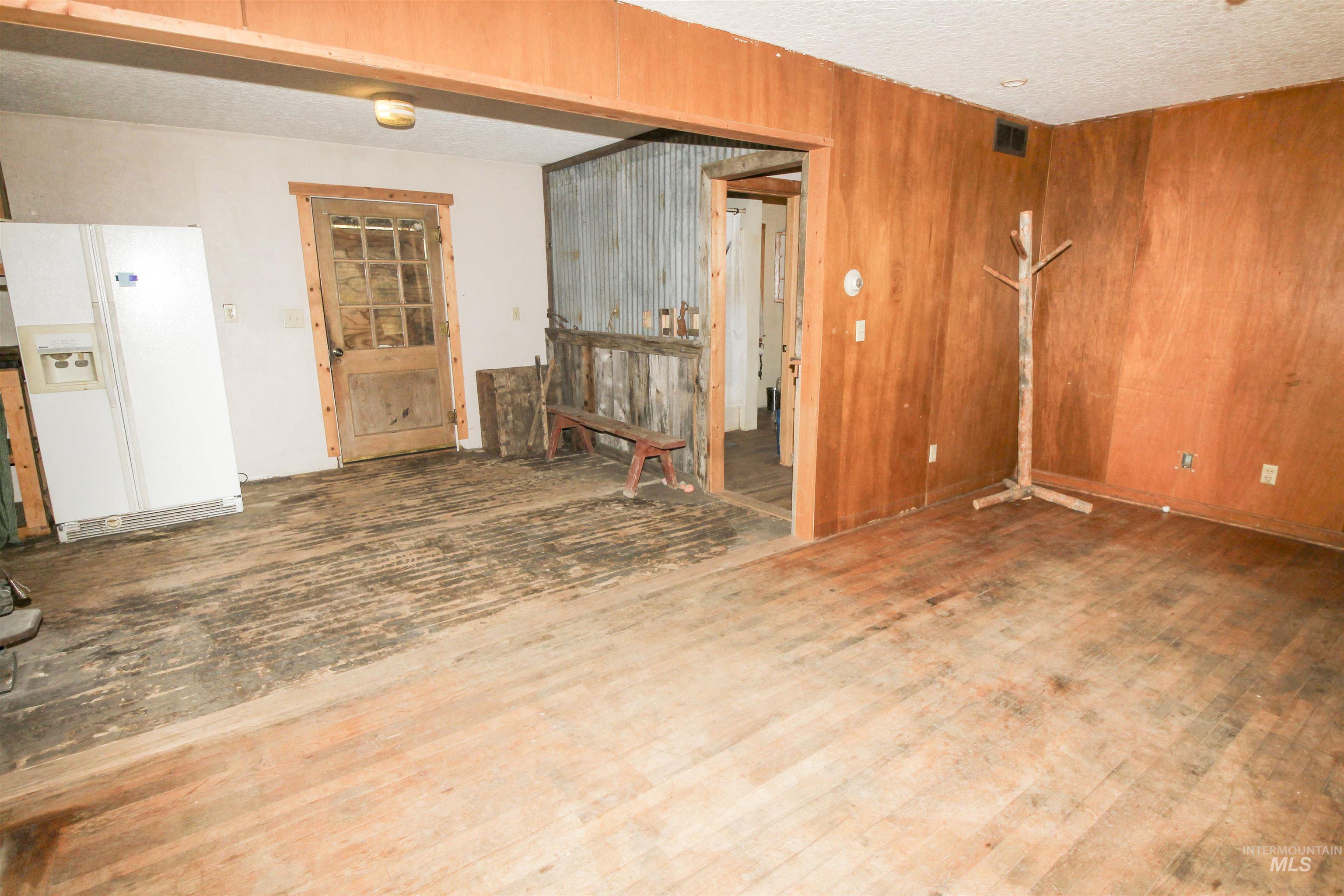 Unfurnished room with wood walls, a textured ceiling, and wood finished floors