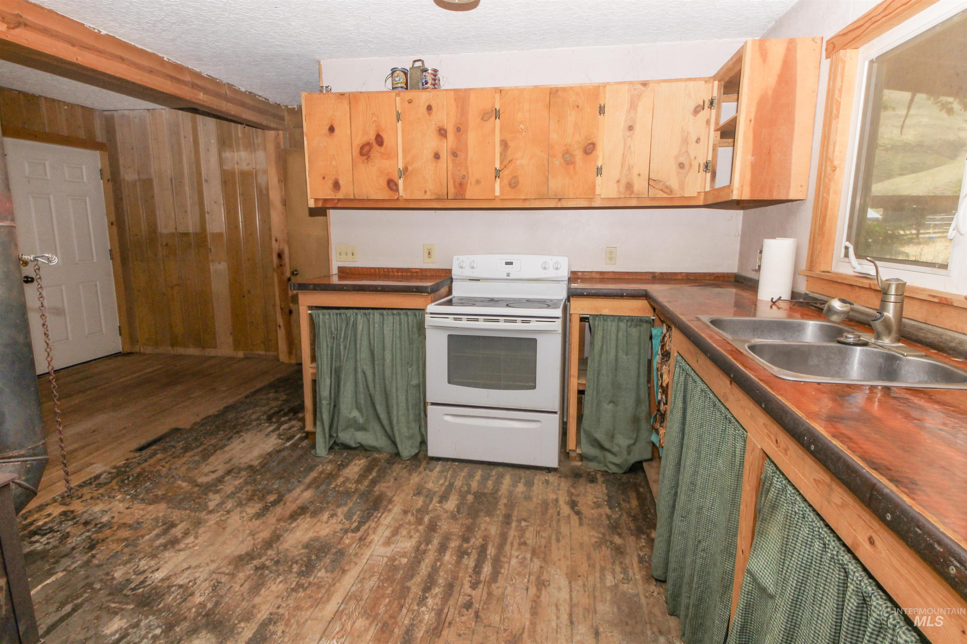 Kitchen with green cabinets, electric range, dark wood finished floors, dark countertops, and a textured ceiling