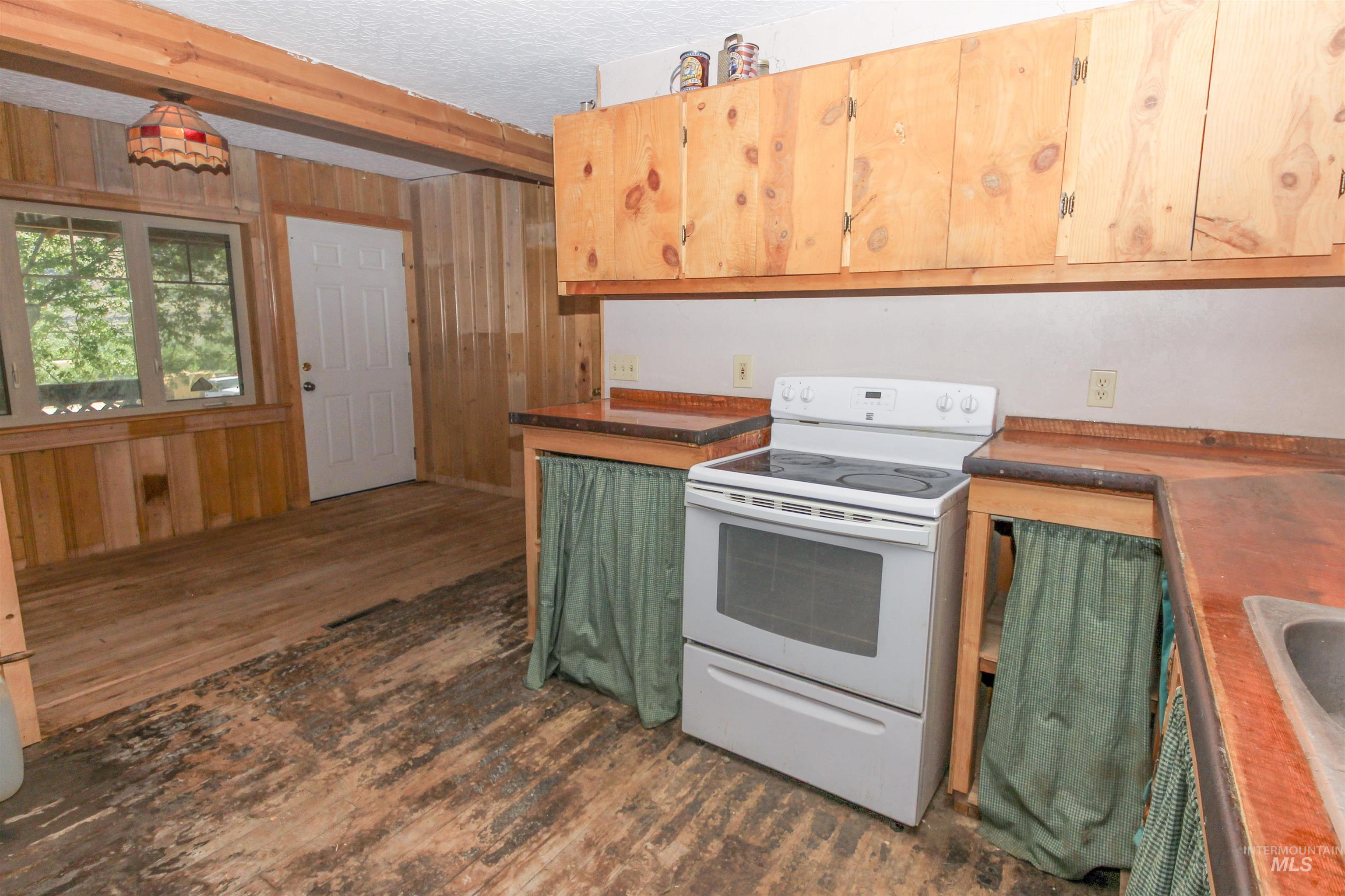Kitchen featuring electric range, dark wood finished floors, green cabinets, beamed ceiling, and dark countertops