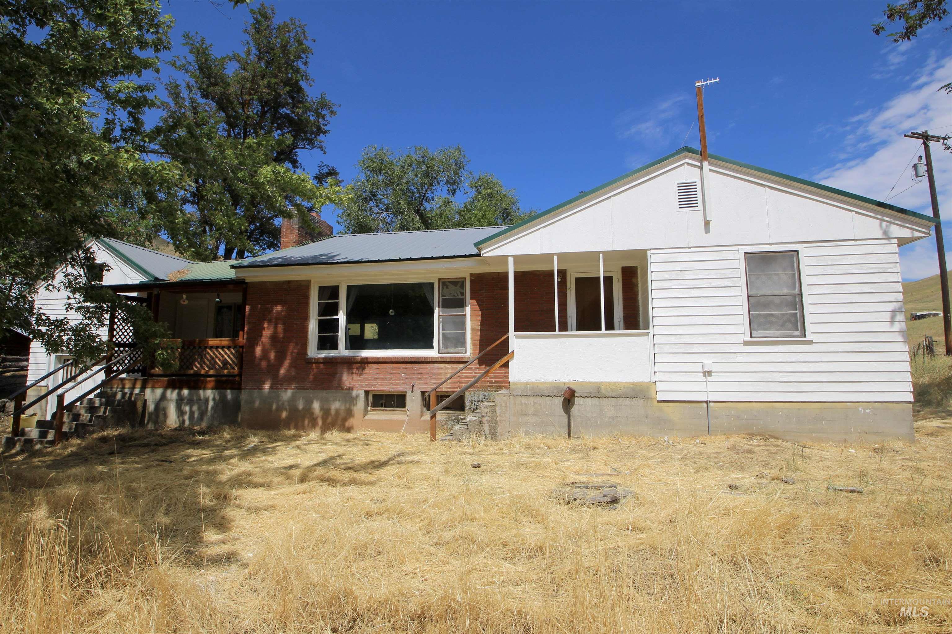 Single story home with a metal roof, stairs, and a porch