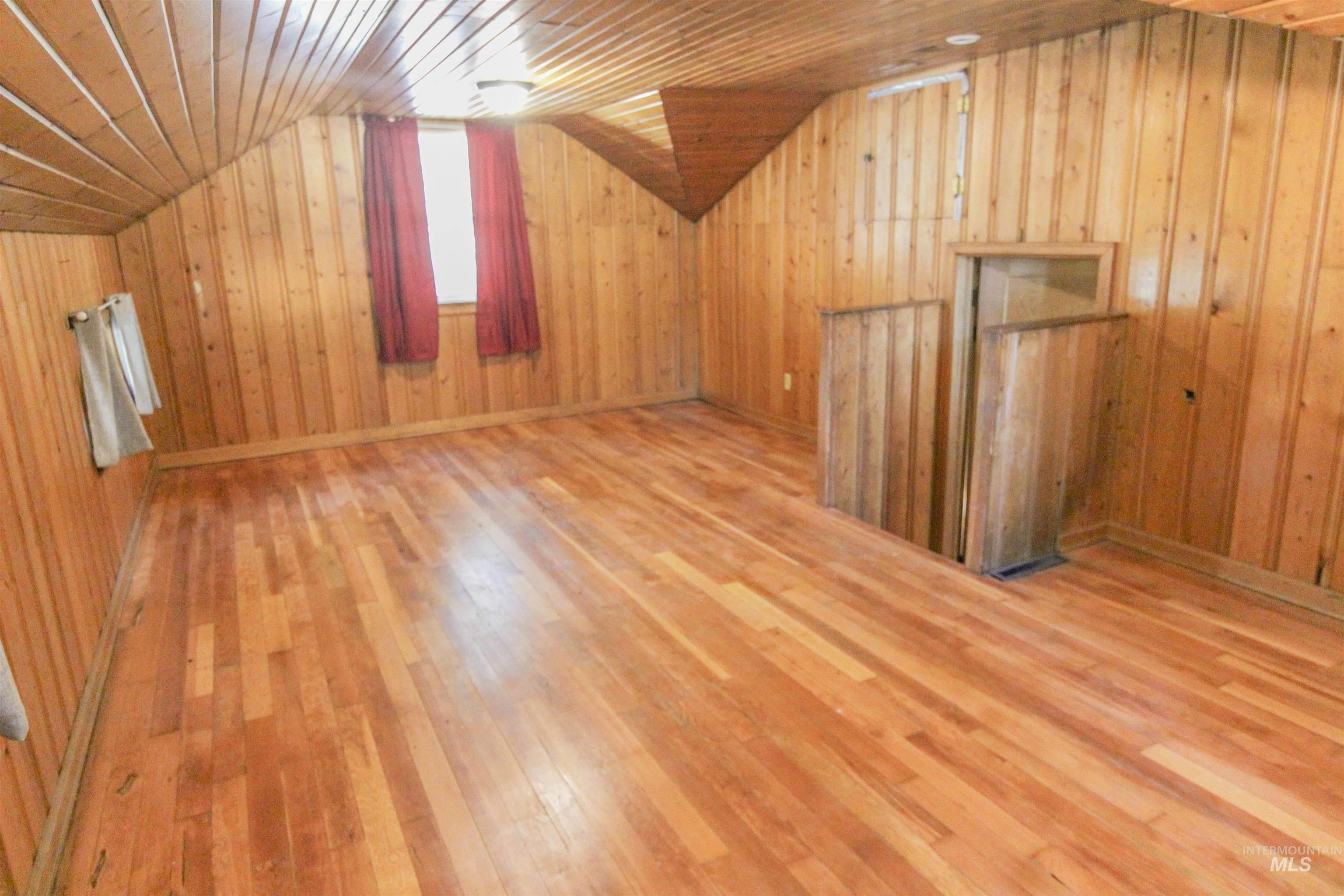 Bonus room with lofted ceiling, light wood-style floors, wooden ceiling, and wooden walls