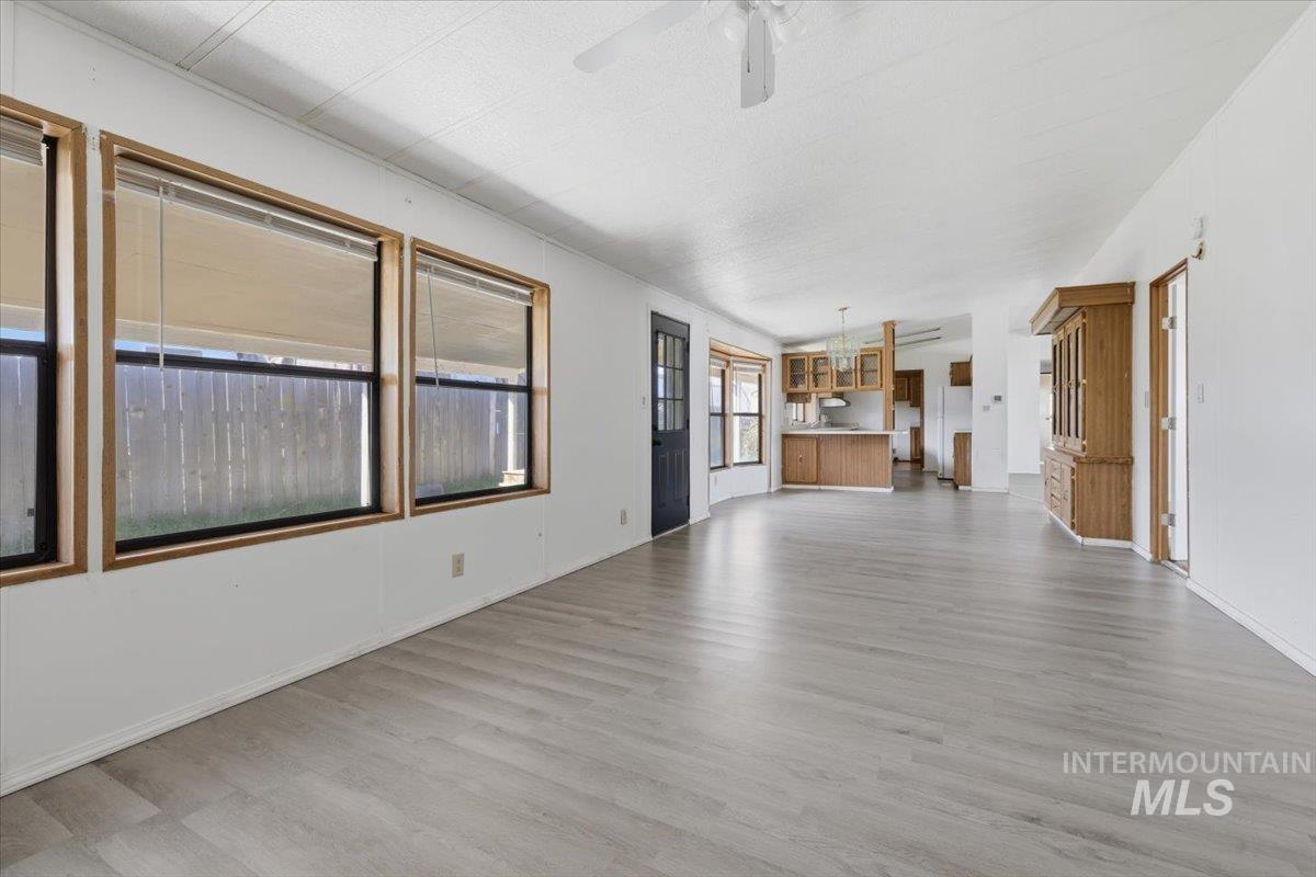 Unfurnished living room with ceiling fan and light wood-style flooring