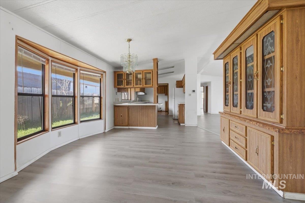 Unfurnished dining area featuring suspended lighting and dark wood finished floors