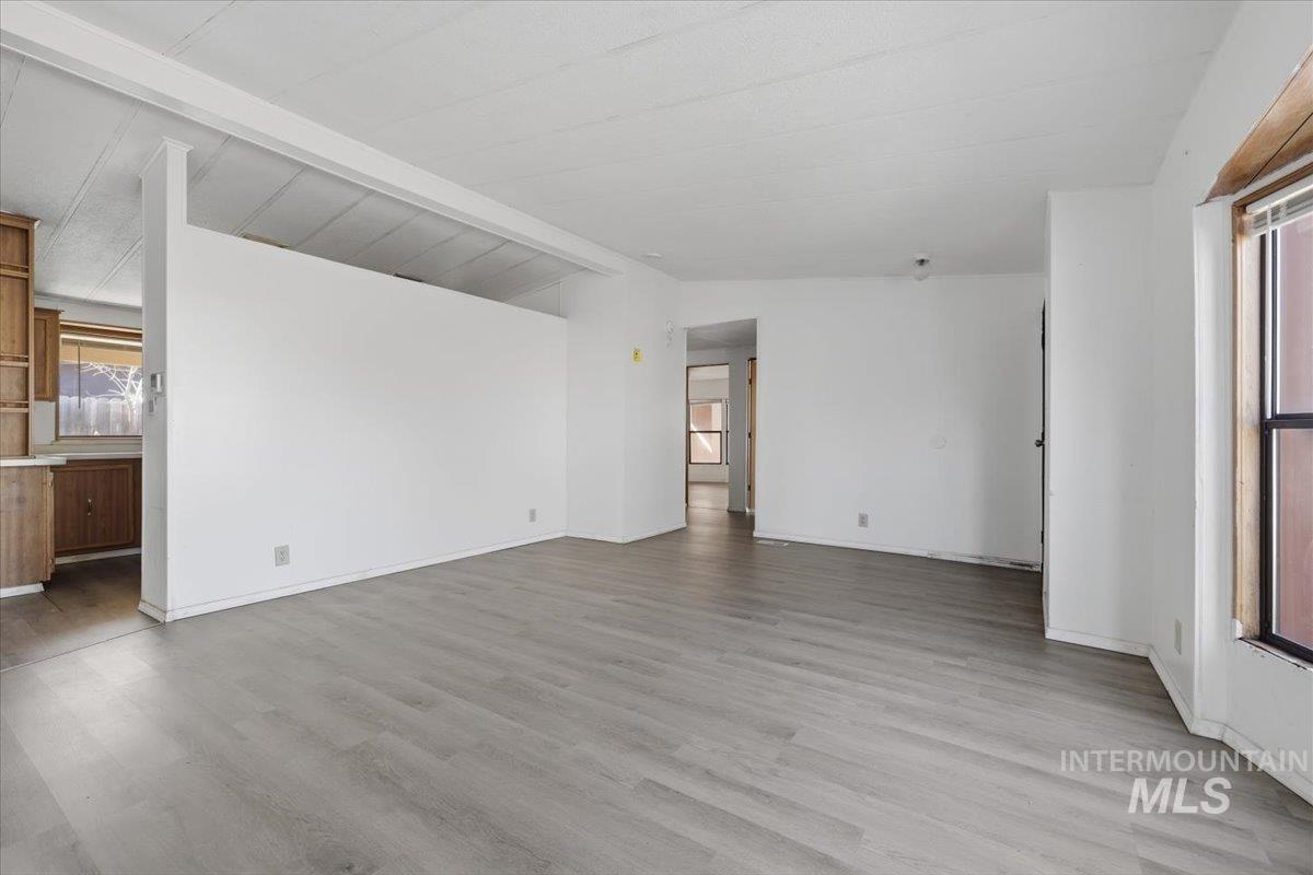 Unfurnished living room with lofted ceiling with beams and light wood-type flooring